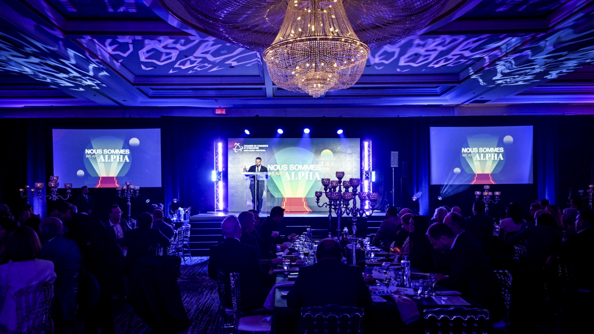 Corporate awards event production at Plaza Volare with full AV setup, including projection screens, ambiance lighting, and LED stage backdrop