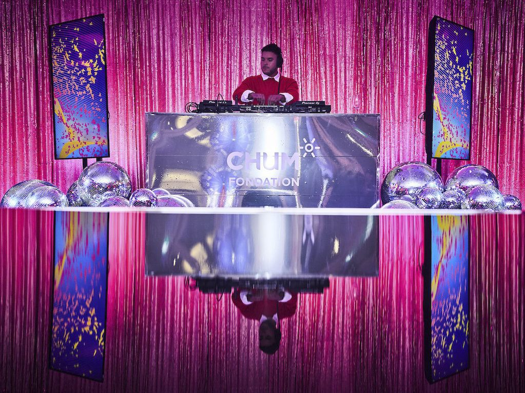 DJ performing at luxury event with chrome DJ booth and hot pink glitter curtain backdrop in Montreal