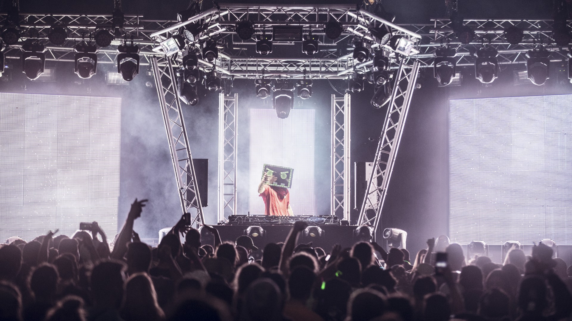 DJ performing on stage with large LED screens, custom truss rig, and professional moving lights and strobe lighting at a Montreal event