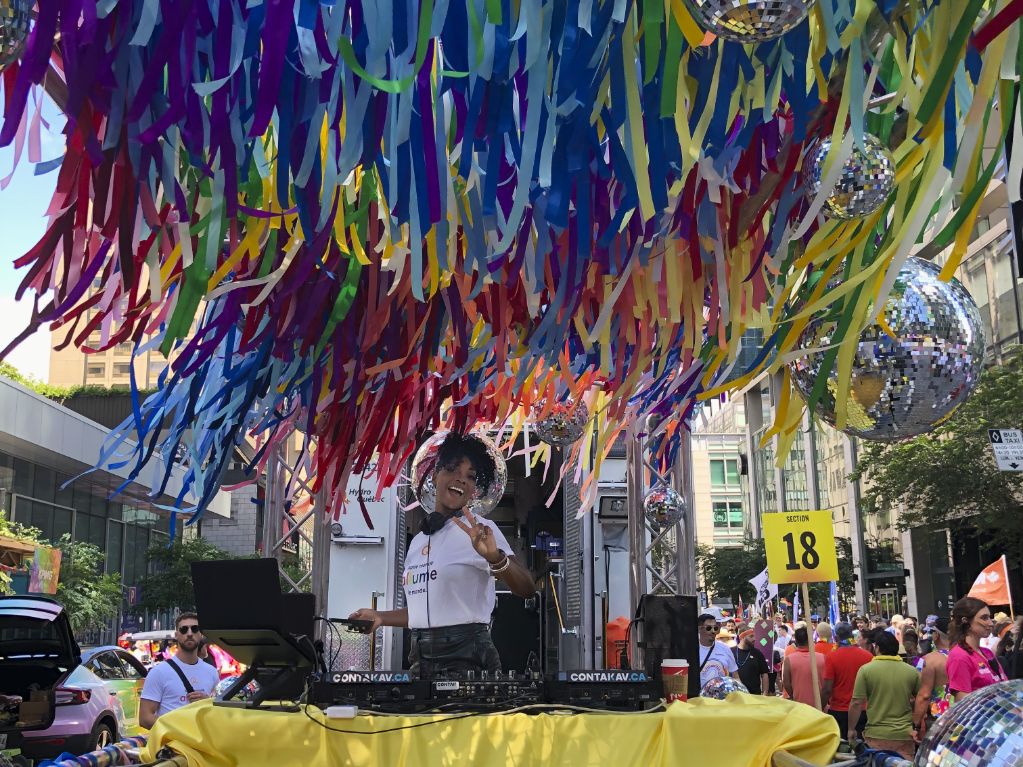 DJ performing on float at Montreal Pride Parade with custom rainbow streamer installation and professional AV setup