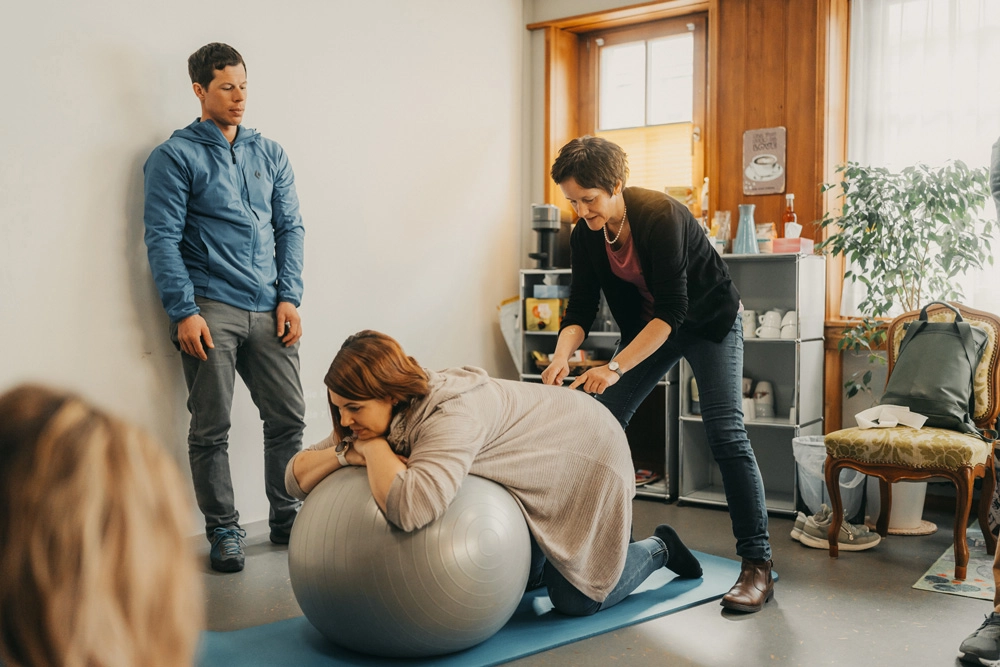 Frau liegt auf einem Gymnastikball im Geburtsvorbreitungskurs