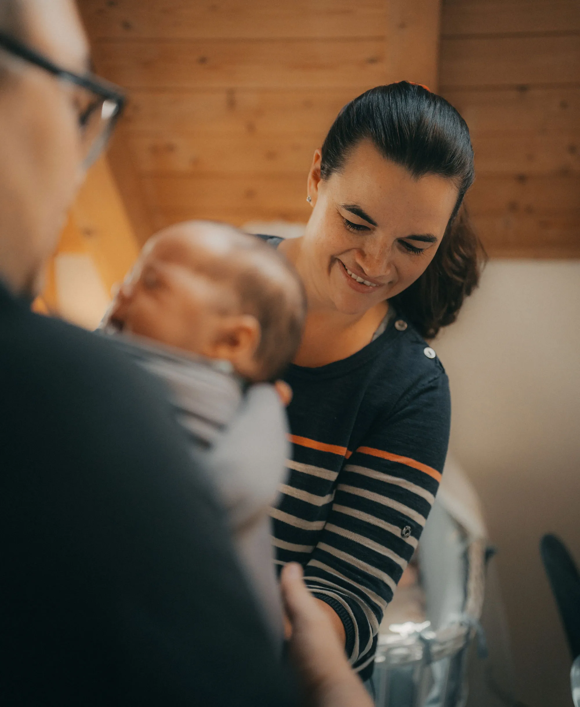 Hebamme hilft dem Vater das Baby in das Tragetuch zu packen