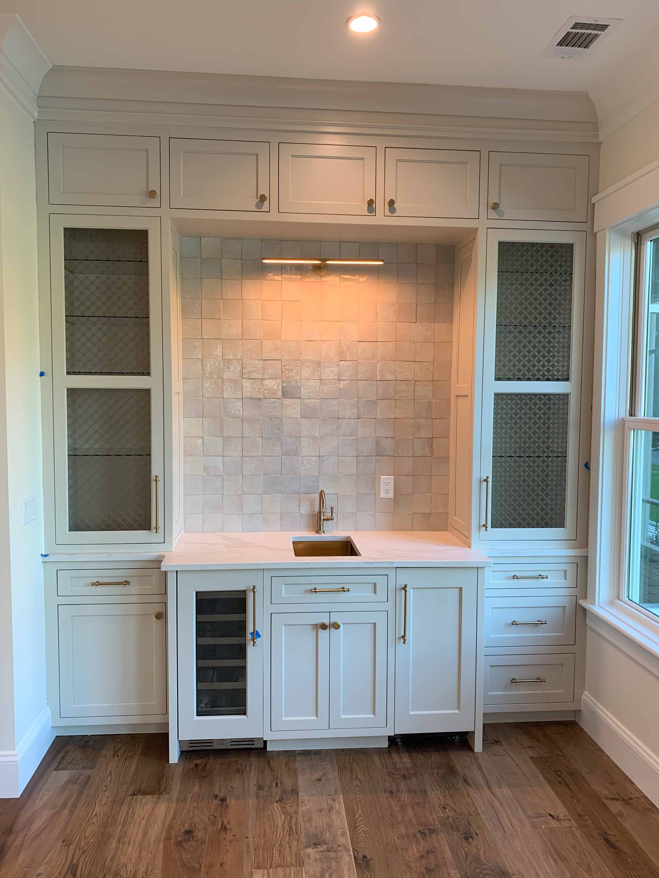 Custom white wet bar cabinetry with glass doors
