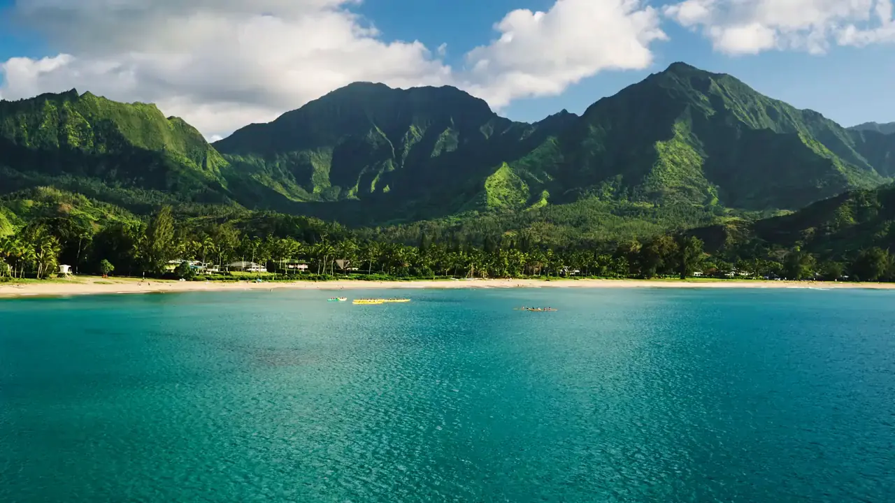 Turquoise bay with a sandy beach and green mountains on Kauai