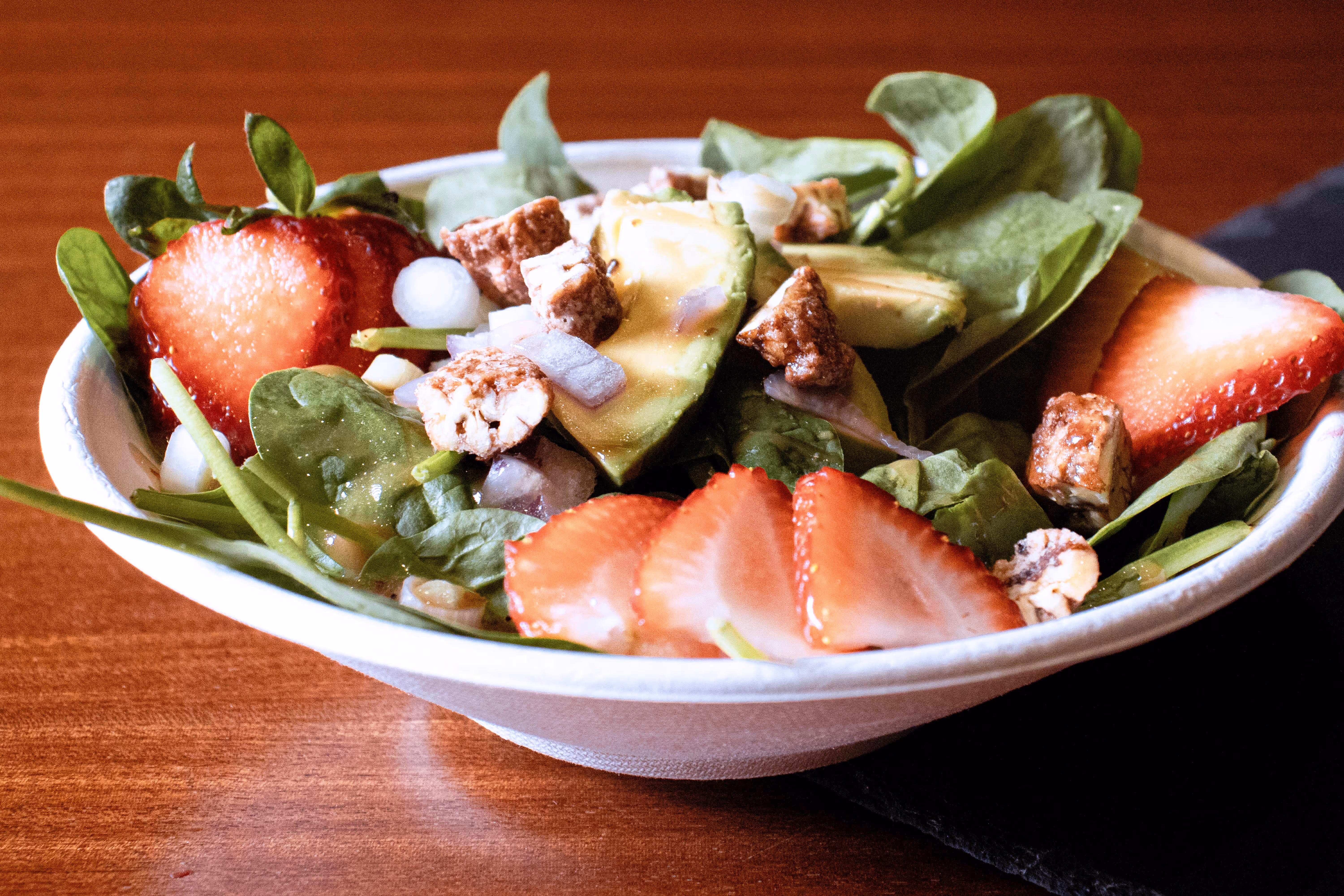 Strawberry summer salad from Old Route 69 Brewery in Ada, Ohio, featuring bistro butter lettuce topped with fresh strawberries, candied pecans, crumbled feta cheese, and a drizzle of raspberry vinaigrette.