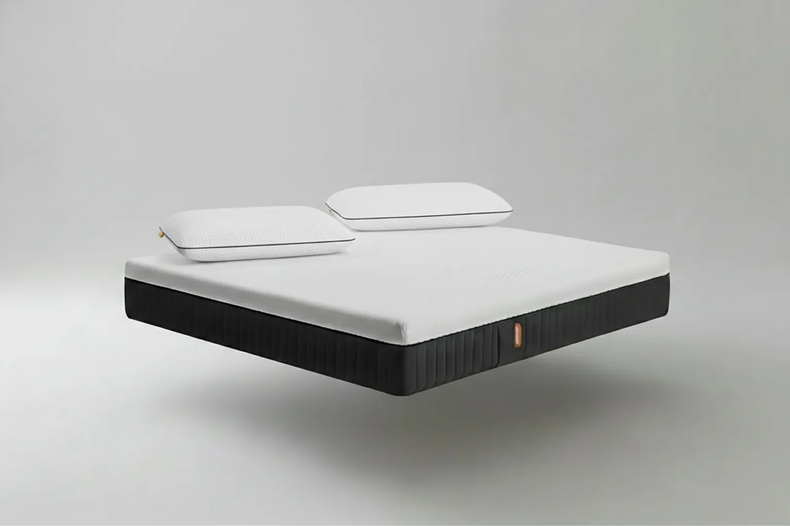 Colchón individual Emma Hybrid Premium memory foam con lateral negro texturizado y etiqueta naranja más dos almohadas