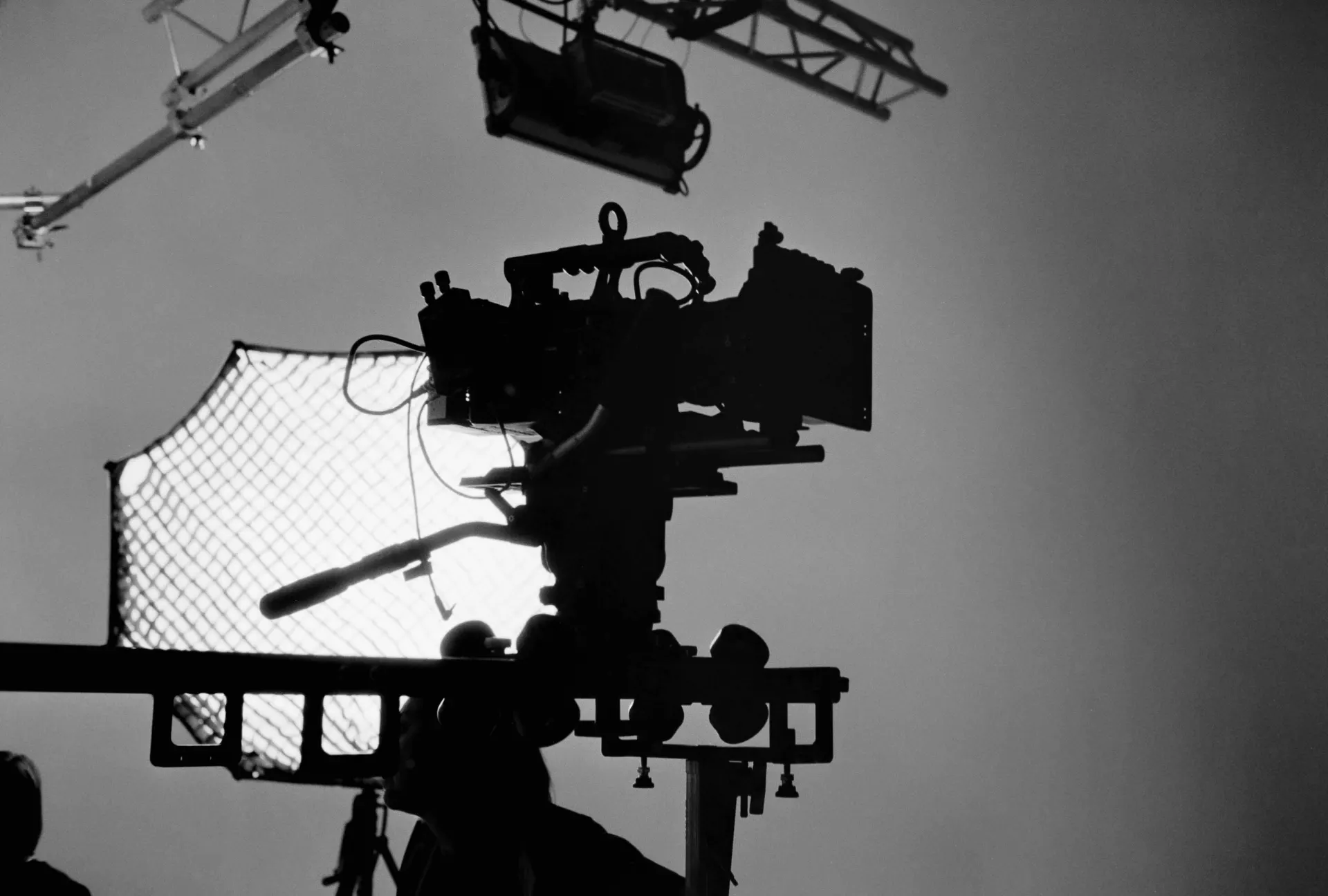 A cinema camera silhouette in front of a large light. On set of a production.