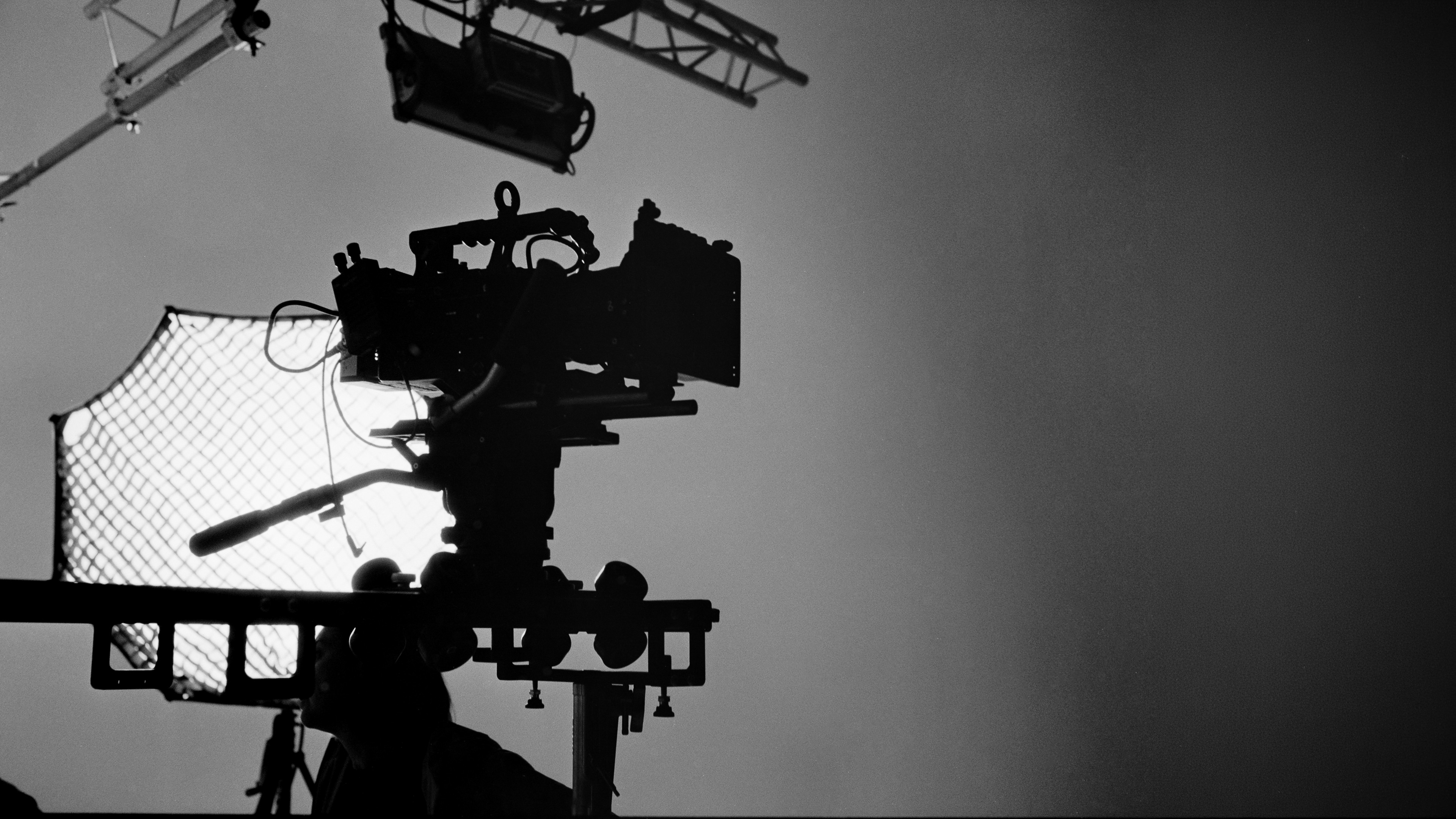 A cinema camera silhouette in front of a large light. On set of a production.