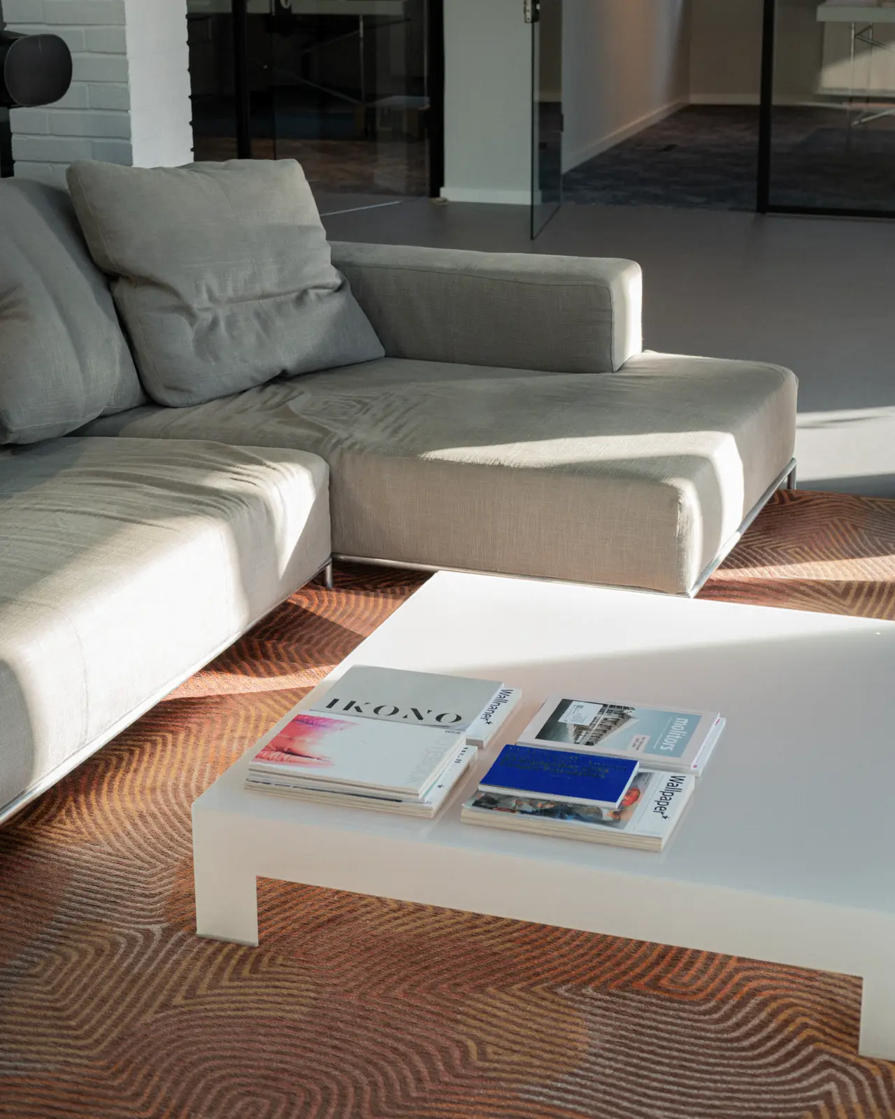 A bright living room with beige sofas and books on a low table.