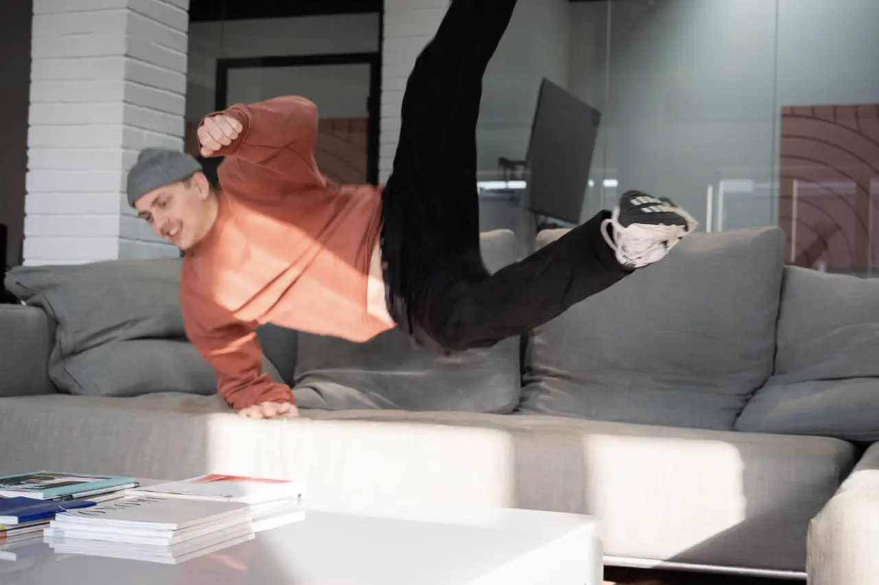 A person jumping or falling backward playfully onto a couch.