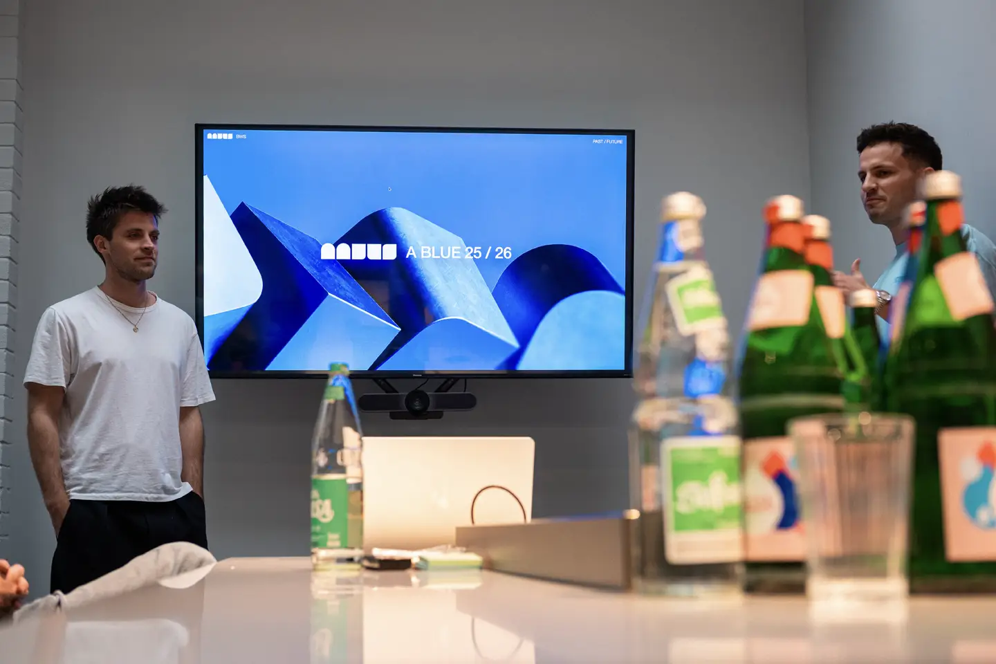 Two people in front of a TV holding a recap presentation.