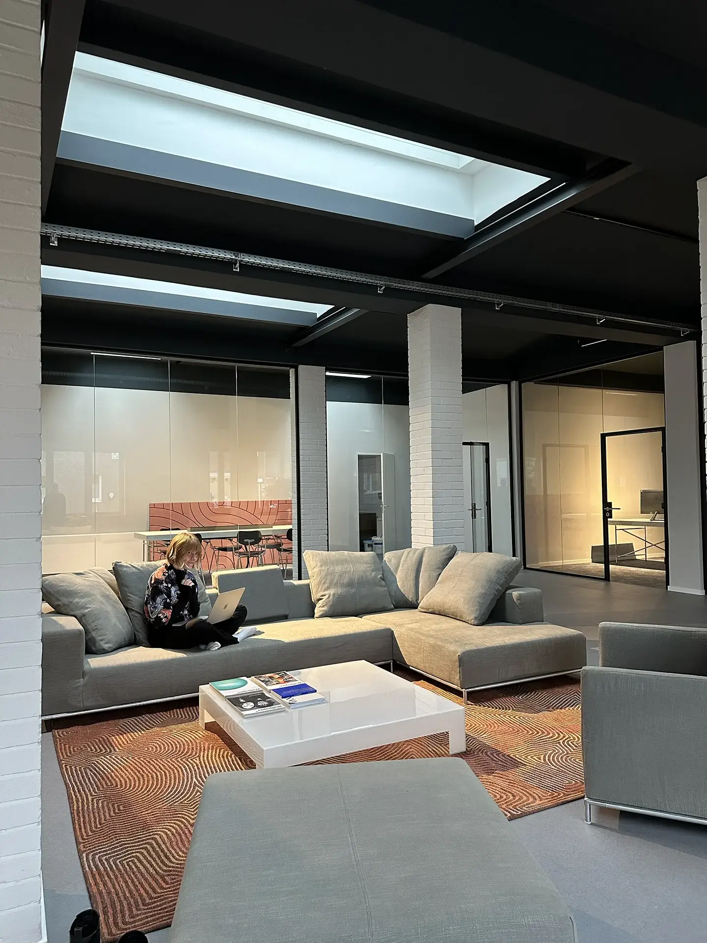 A look into our new office with a person sitting on a large grey couch.