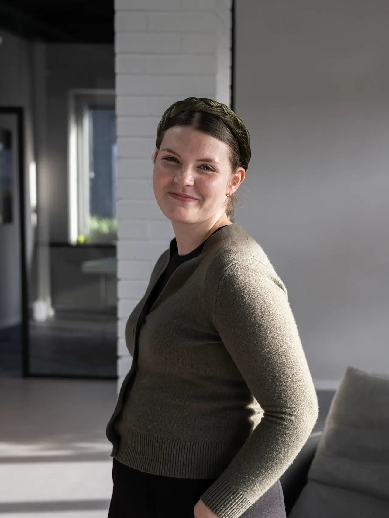 Portrait of a team member standing and smiling in a modern office.