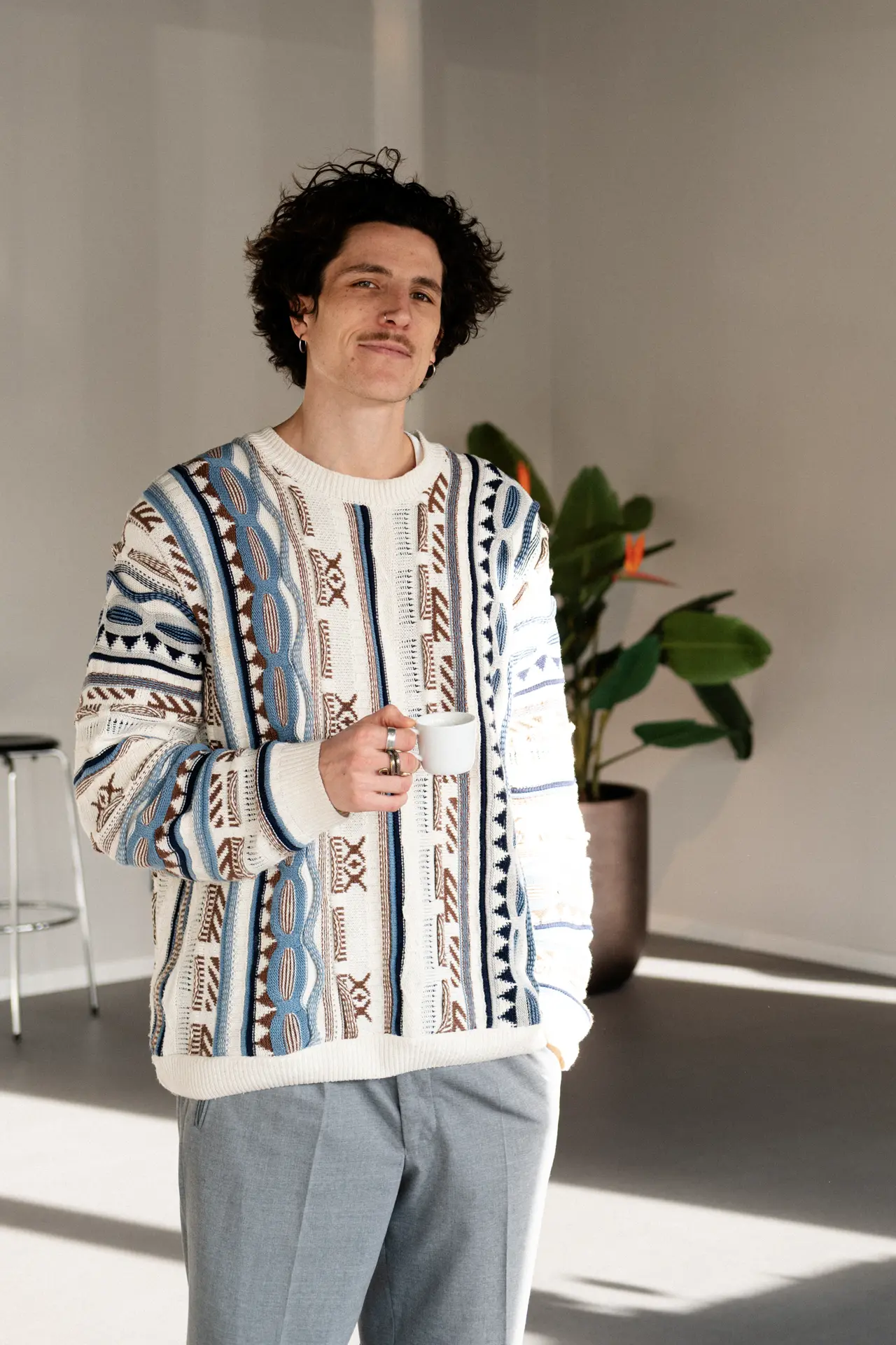 Miguel steht vor einer Strelitzie und hält einen Espresso in der Hand.