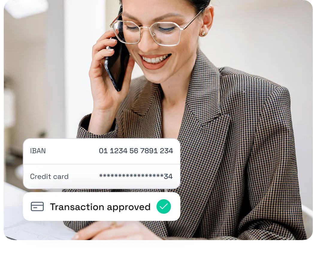 Smiling woman wearing glasses and a checkered blazer talking on a phone with an overlay showing approved transaction details including masked credit card and IBAN number.