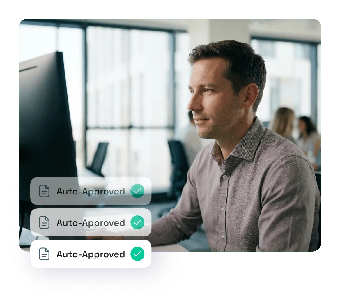 Man working on a computer in a modern office with three layered 'Auto-Approved' icons displayed beside him.