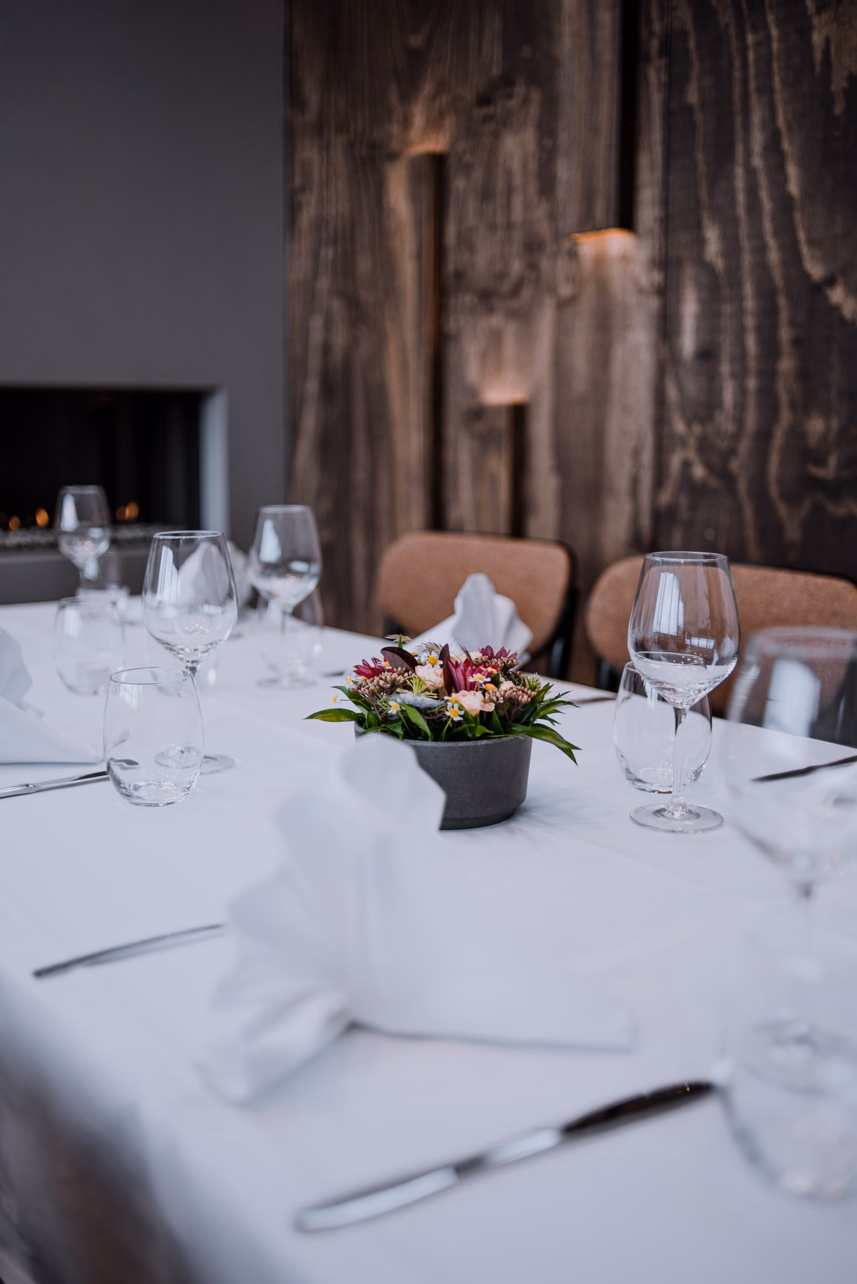 Table set with folded white napkins, glassware, and a floral centerpiece in a cozy dining room.