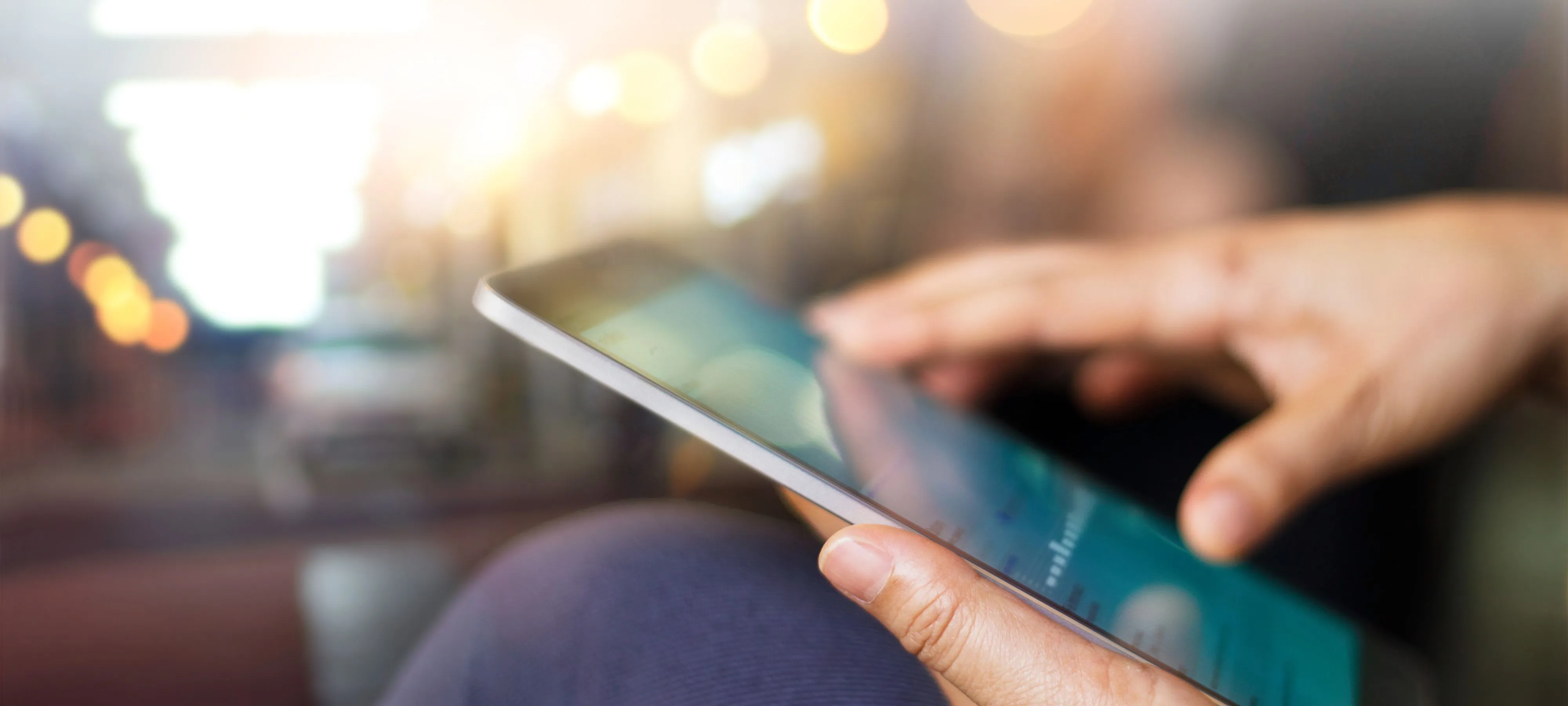 Person hält ein iPad in der Hand, Hintergrund unscharf