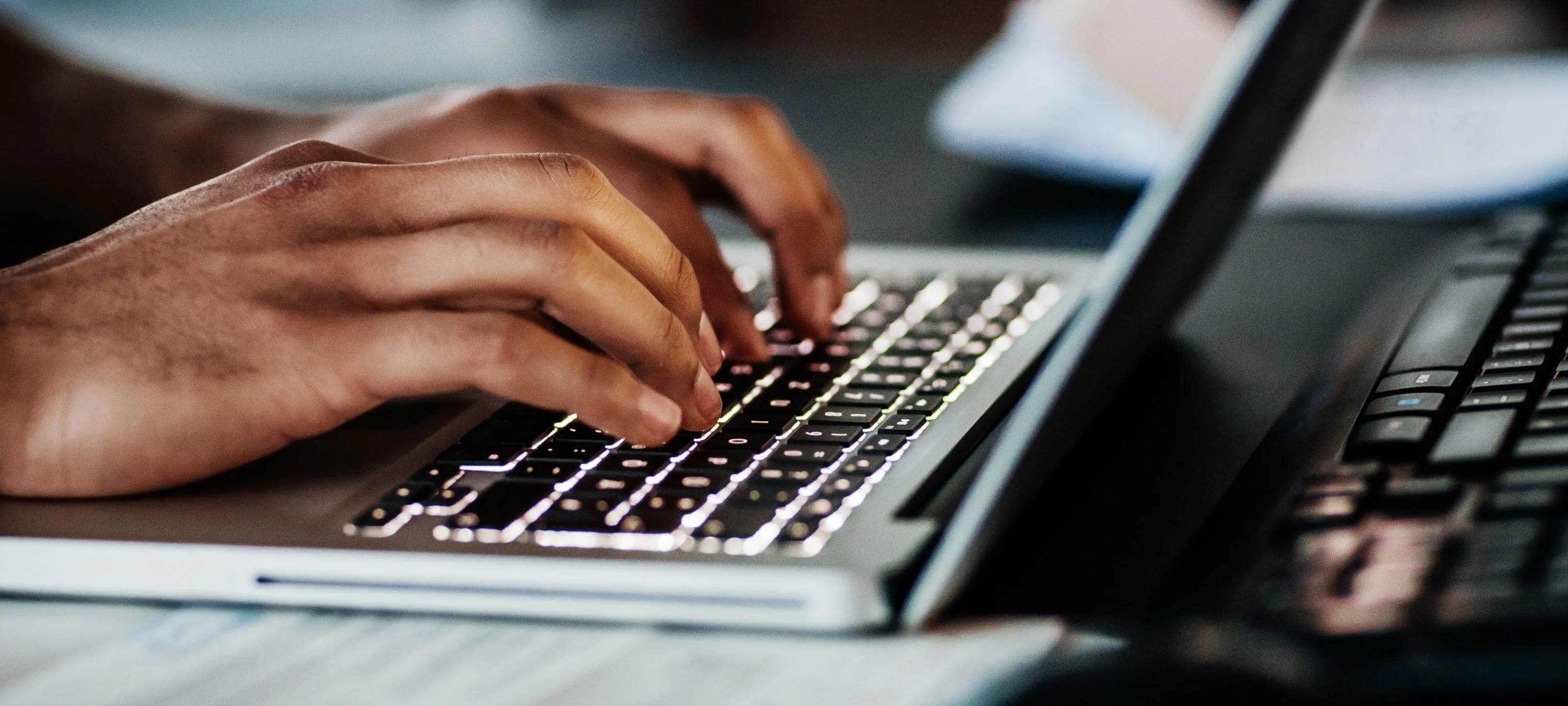 Person tippt auf einem Laptop, fokussierte Hände auf der Tastatur