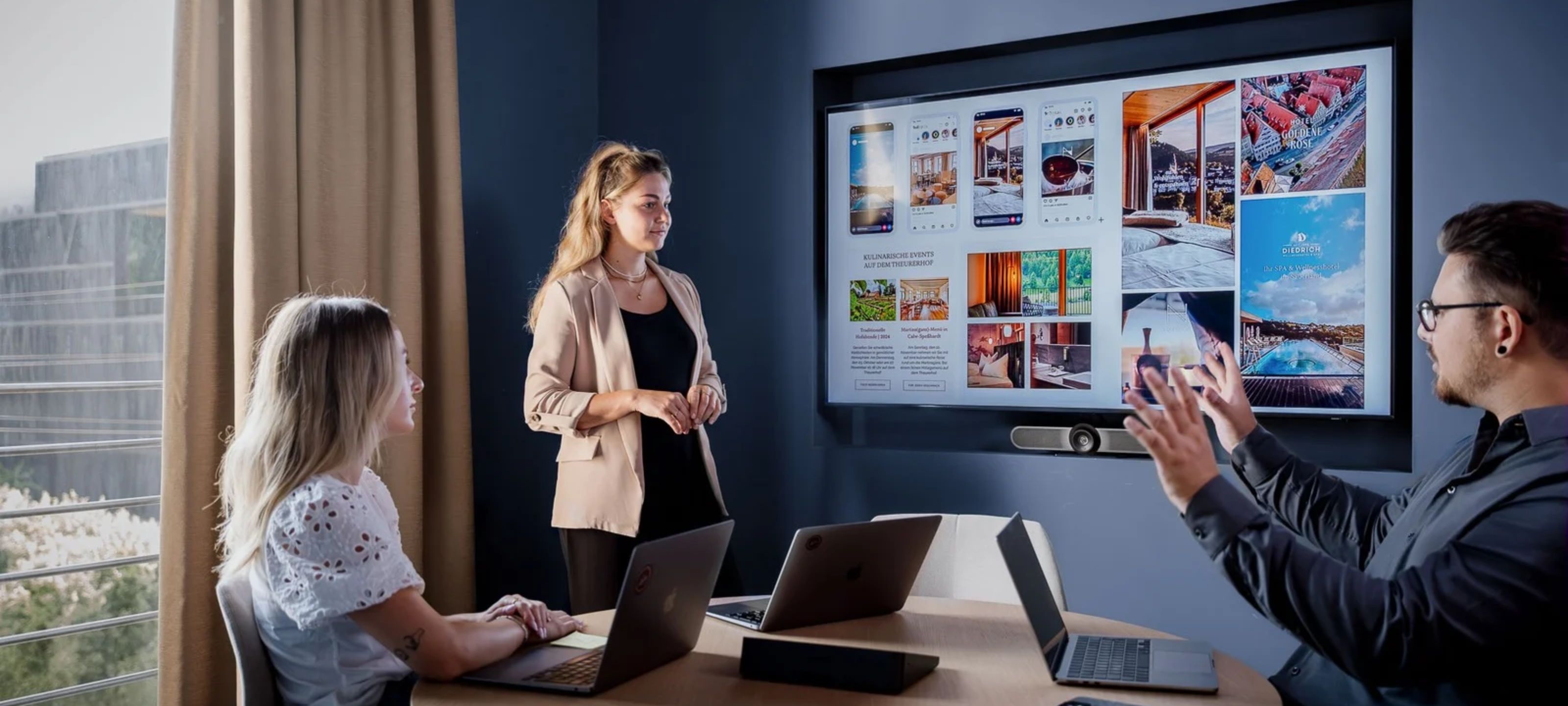 Drei Experten von ADDITIVE besprechen die Werbemittel-Strategie für ein Agenturkonto, während auf einem großen Monitor verschiedene Hotel-Impressionen und Social-Media-Anzeigen analysiert werden.