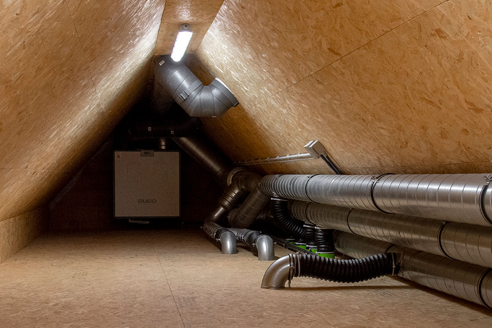 Zolderkamer met buizen en unit dat voor de ventialtie zorgen