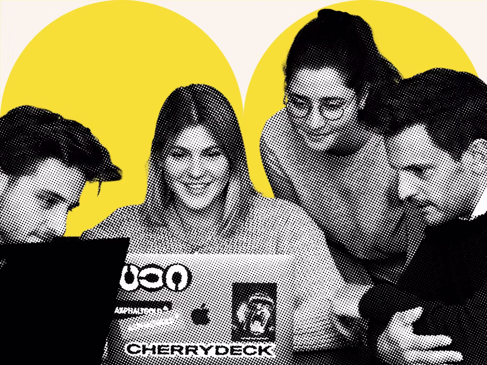 Halbton-Aufnahme: vier Personen blicken gemeinsam auf einen Laptop, vor einer Happy-Lemon-Fläche