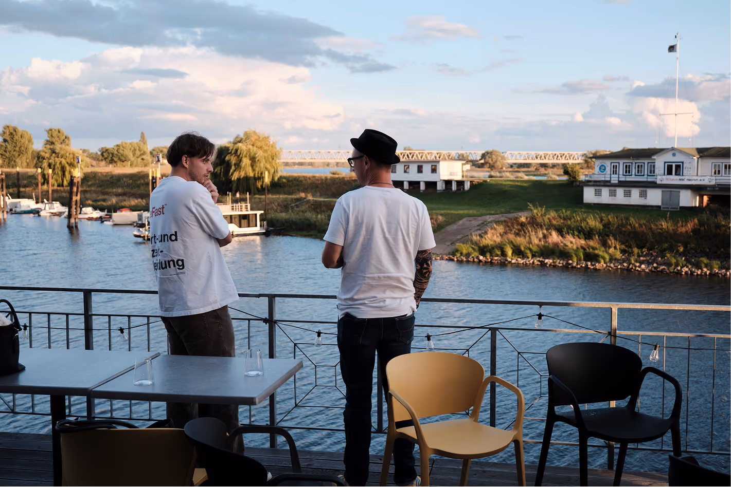 Zwei Kollegen im Gespräch an der Brüstung mit Blick auf den Fluss