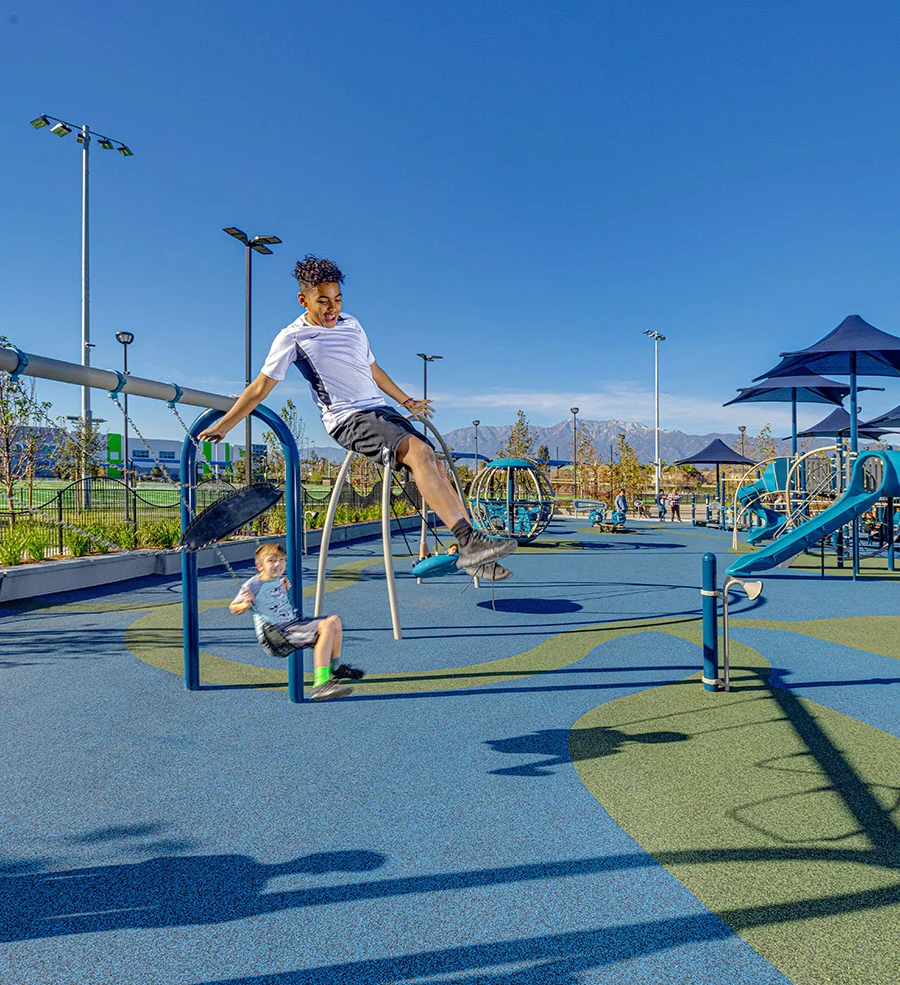 Parks and recreation projects: two children using playground exercise equipment on a blue play surface