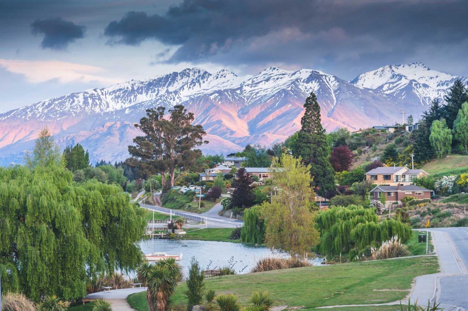 A small town in New Zealand. There are trees, a calm river and houses surrounded by nature