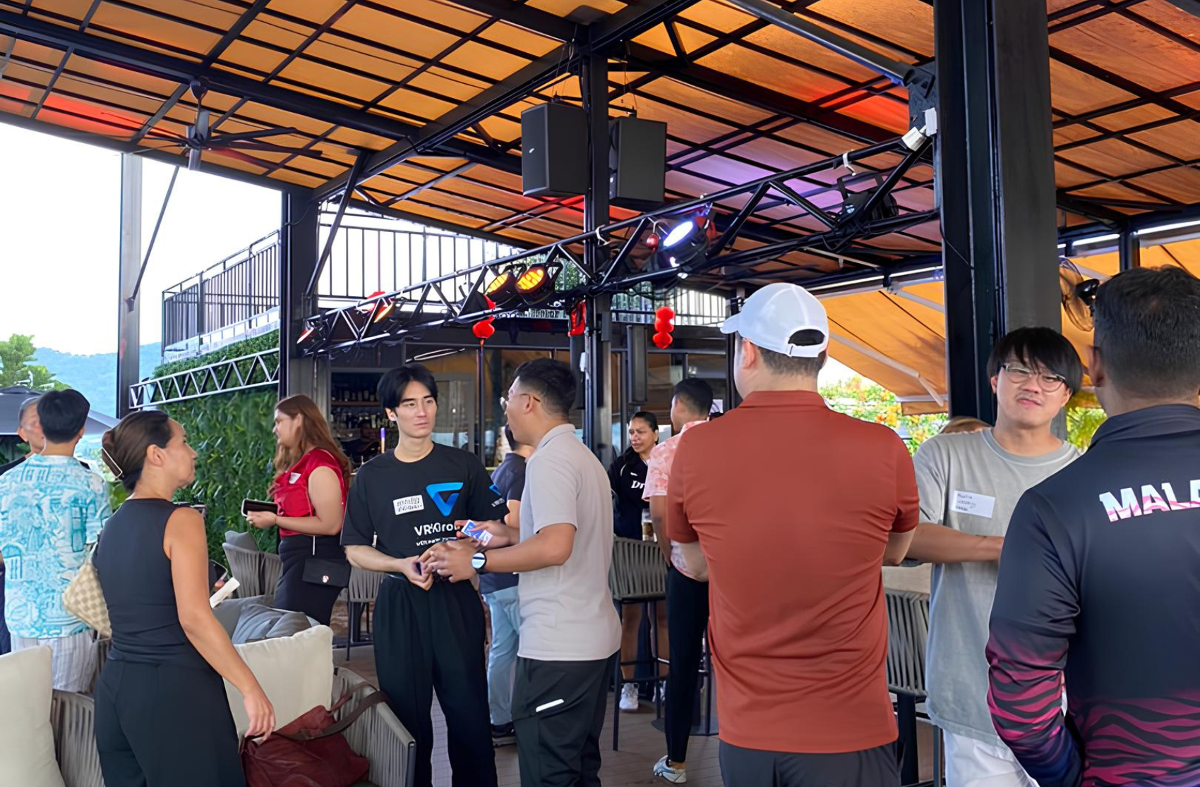 a group of people casually chatting and networking at a modern rooftop lounge with colorful lighting and comfortable seating.