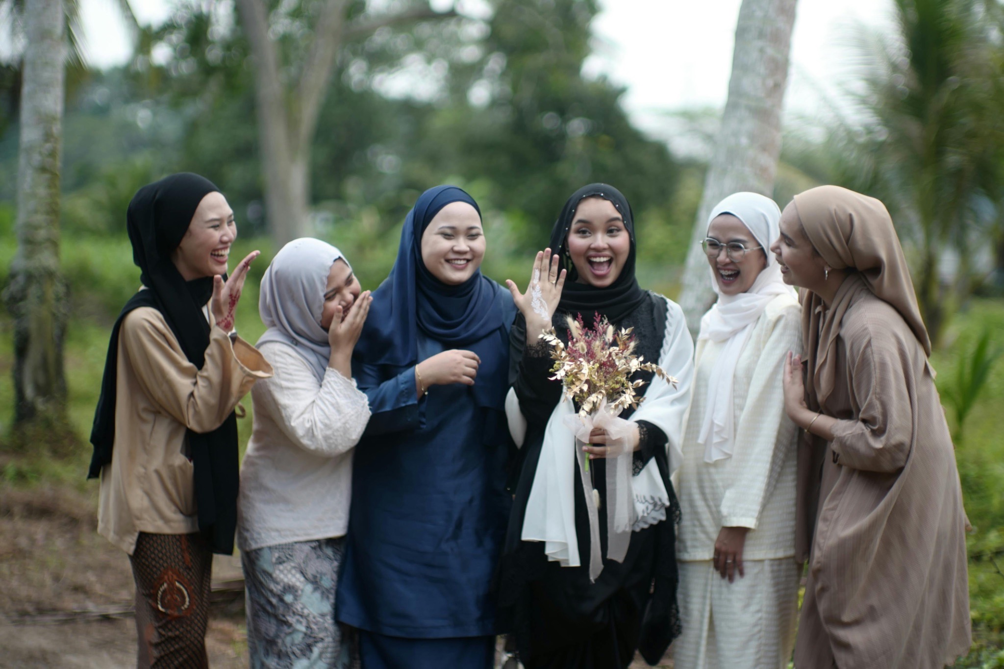 Young Woman Showing Her Engagement Ring while Standing with a Group of Friends 