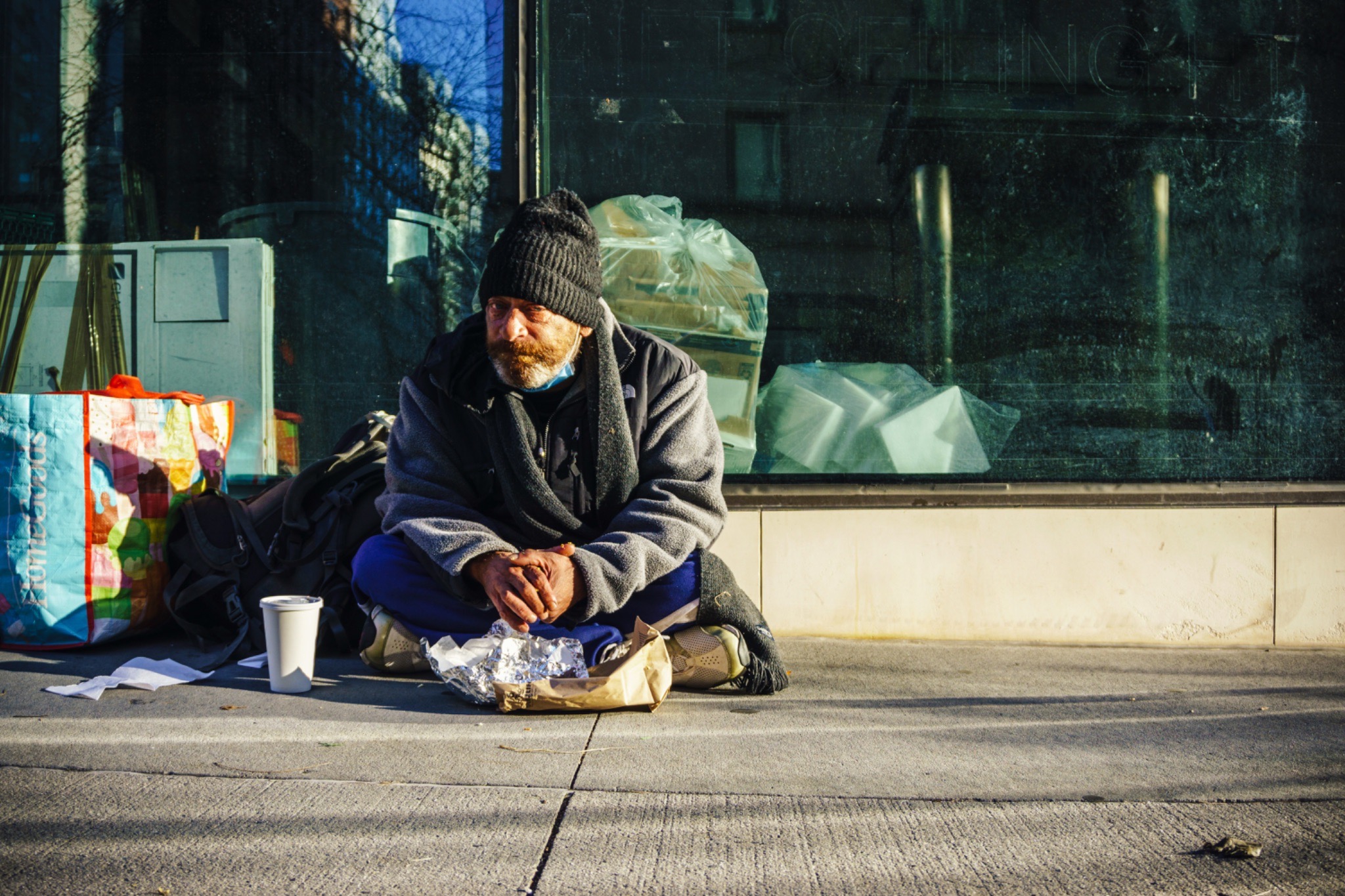 A homeless man eats breakfast on the street on Upper East Side of Manhattan.