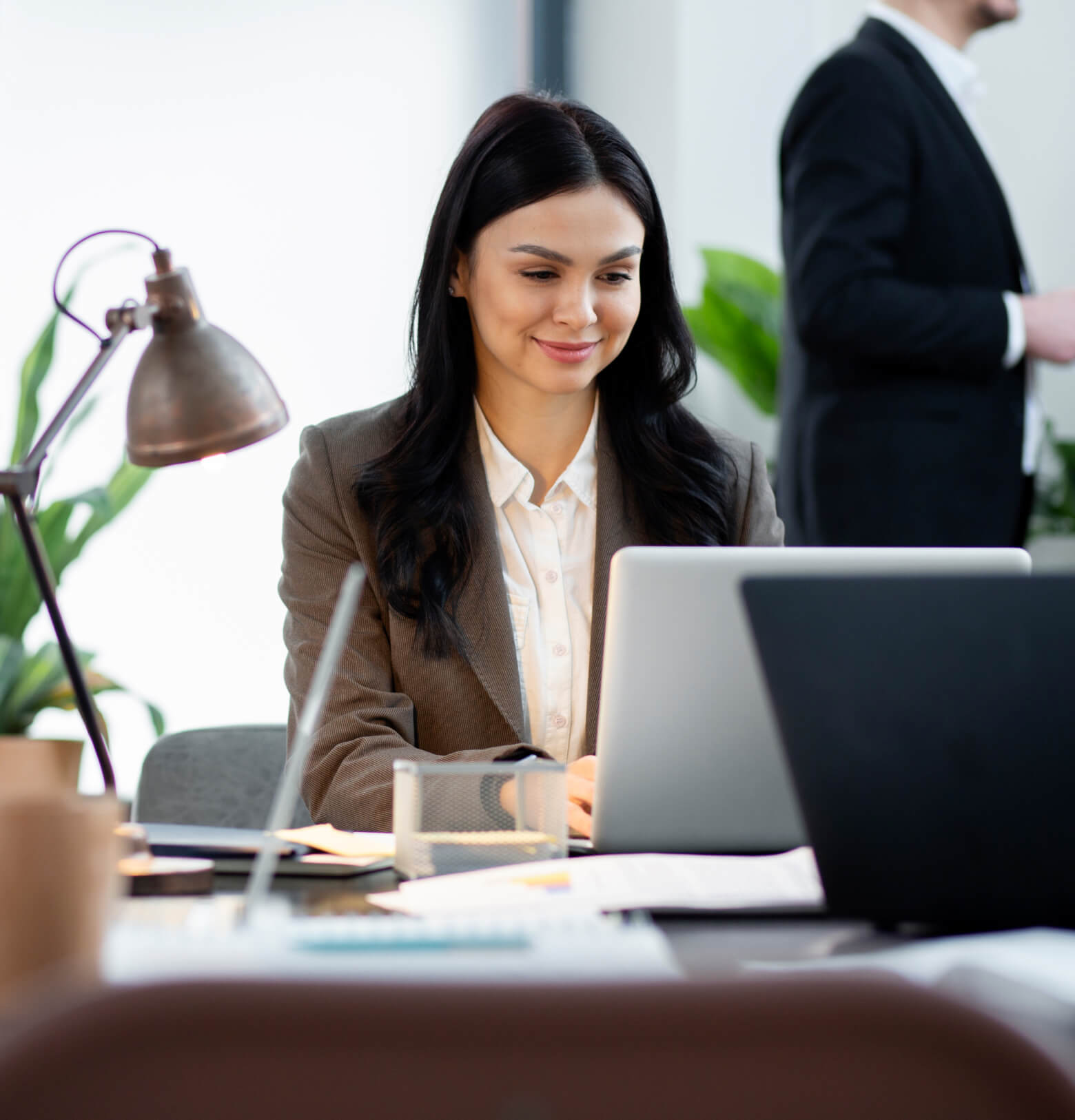 A woman sitting at a desk in front of a laptop computer.