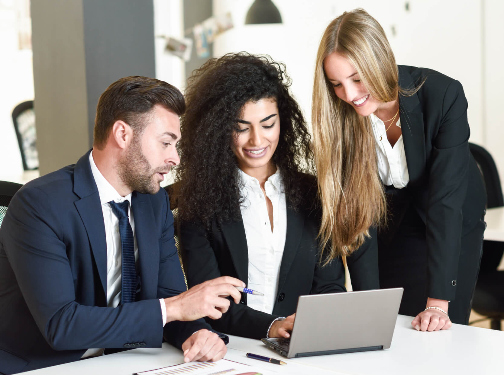 Three business people looking at a laptop screen.