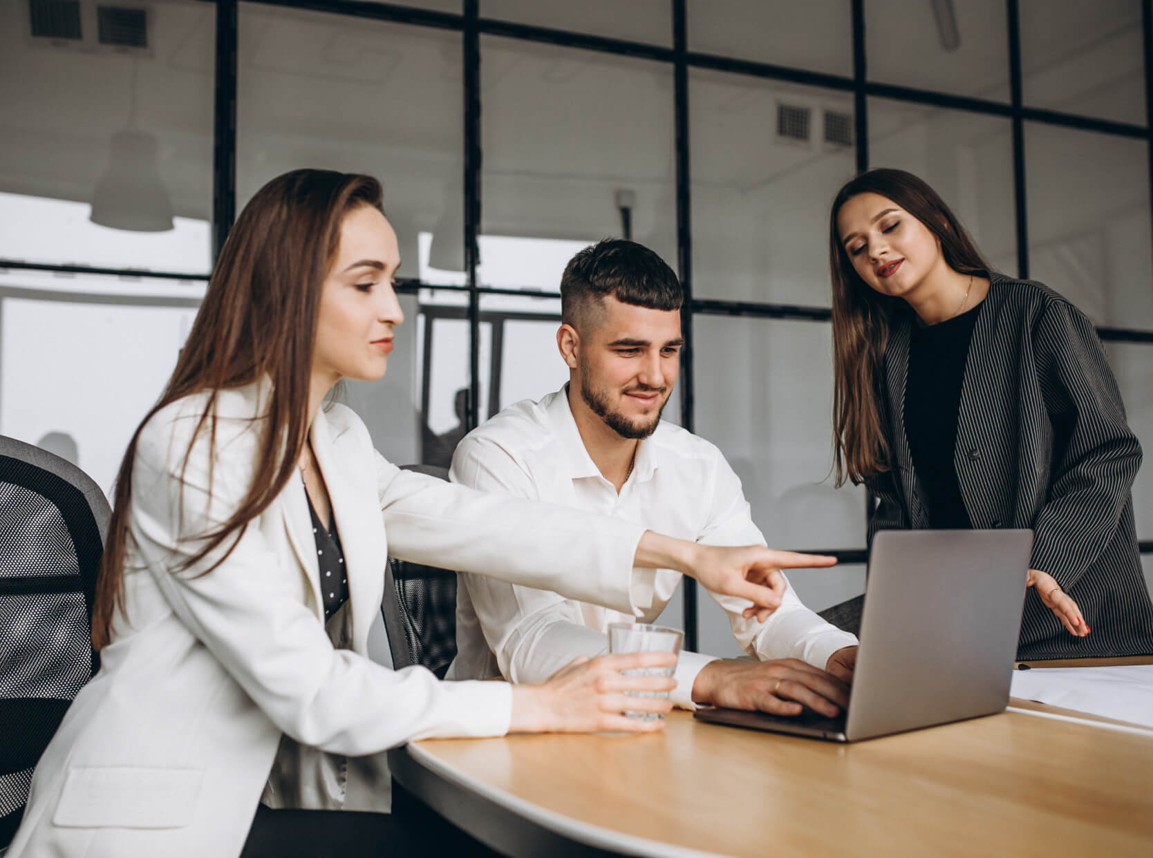 A group of people sitting around a table with a laptop.