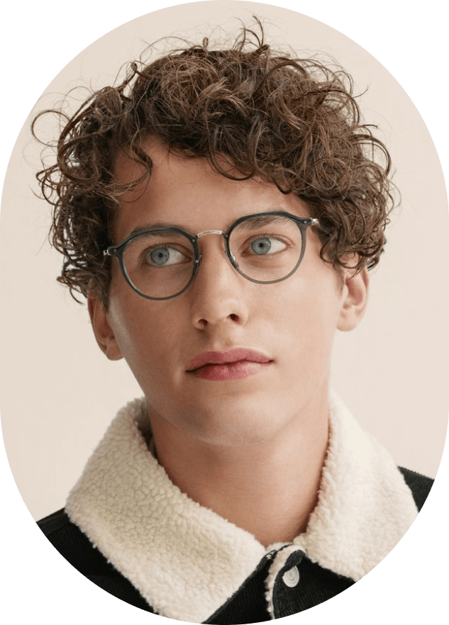 A man with curly hair and glasses looking at the camera.
