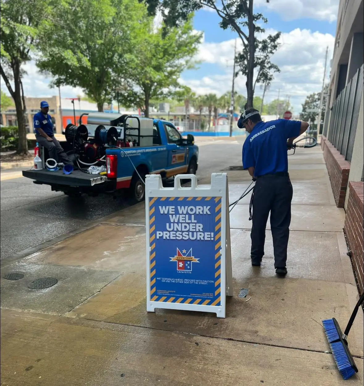 A downtown ambassador pressure washing a sidewalk