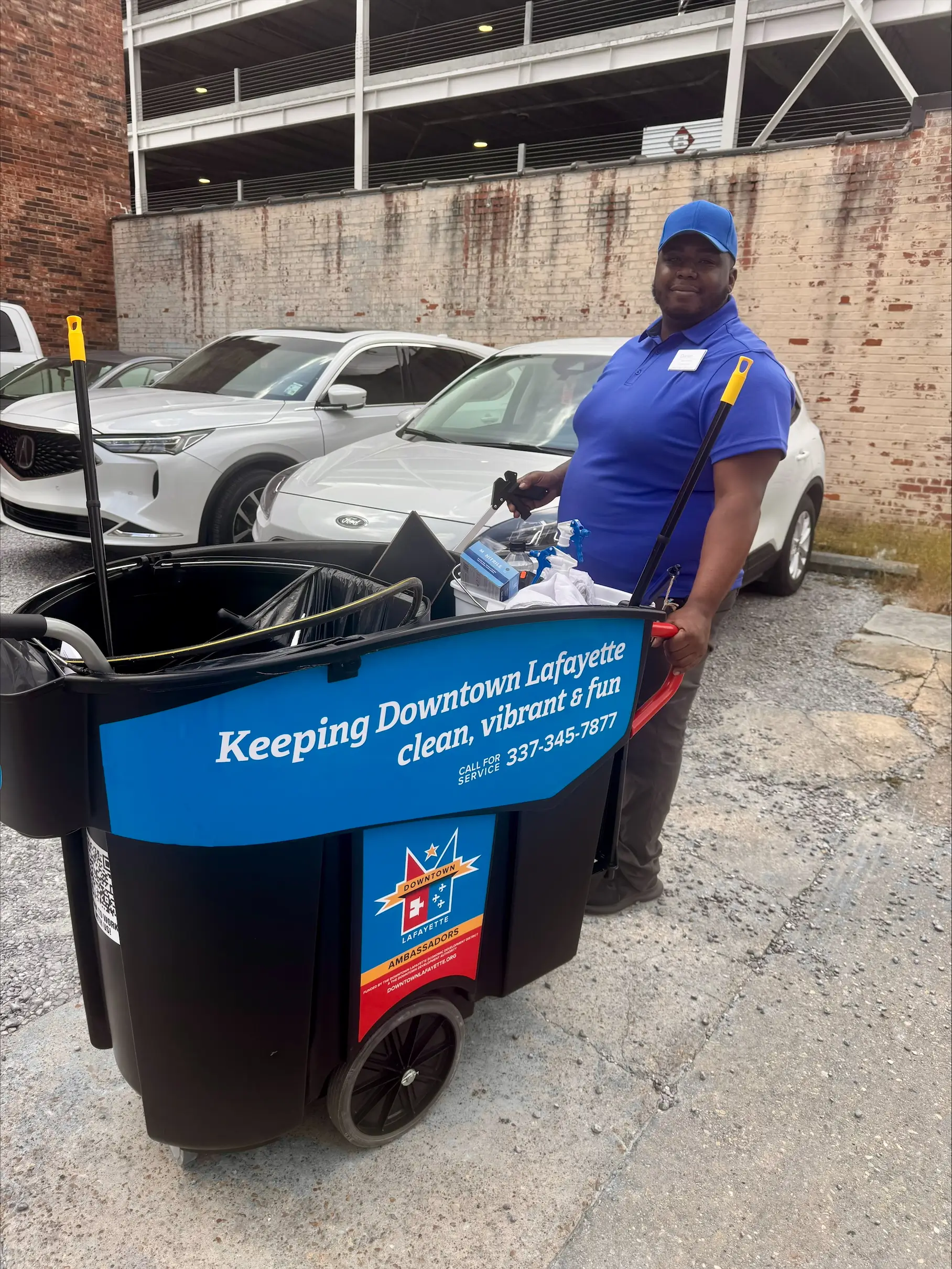 A downtown ambassador stands with a cart for cleaning up downtown