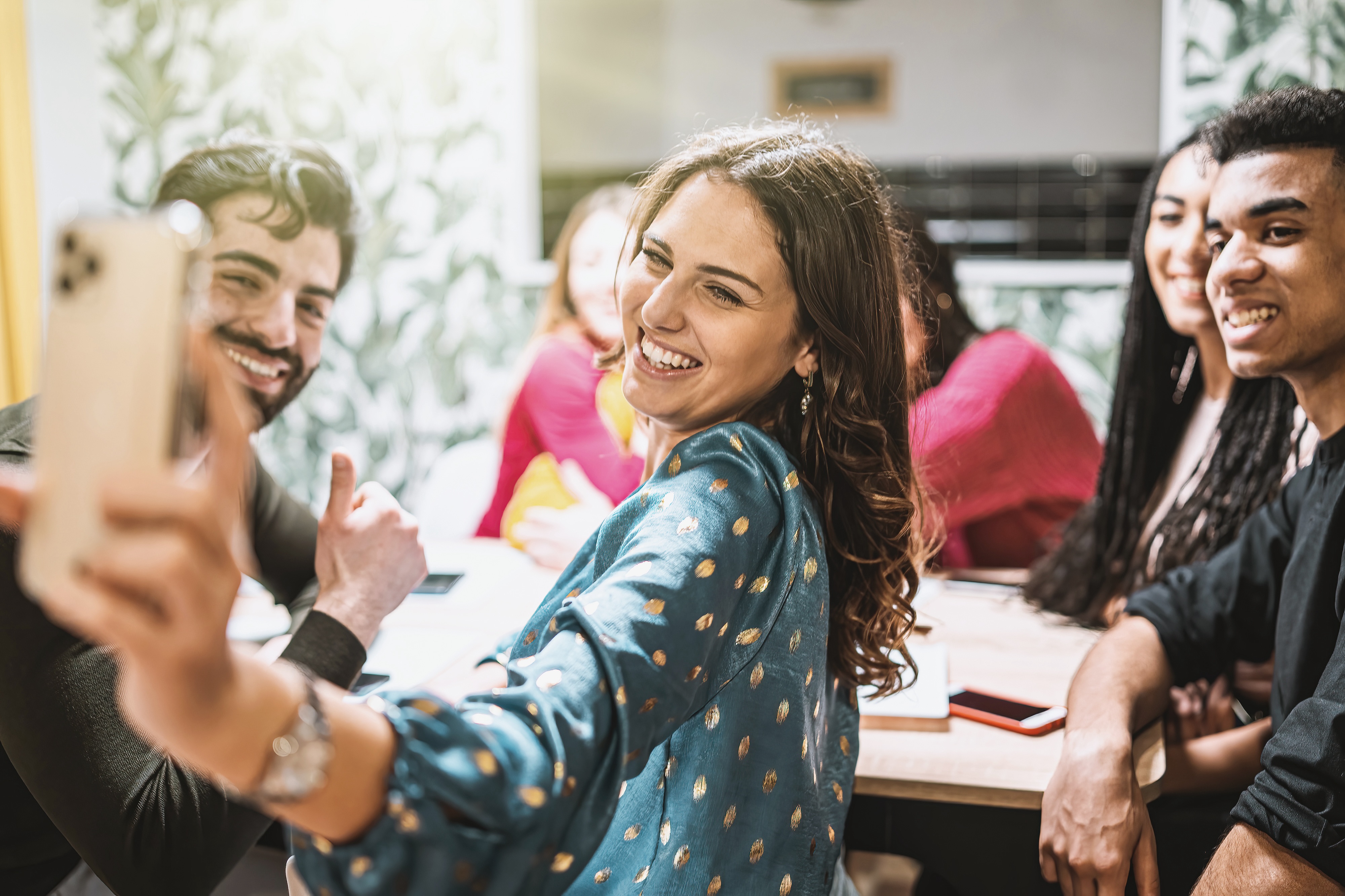Group of happy friends taking a selfie together at a modern table, representing the vibrant community and social opportunities at Iconik Bixby apartments in Bixby, OK.