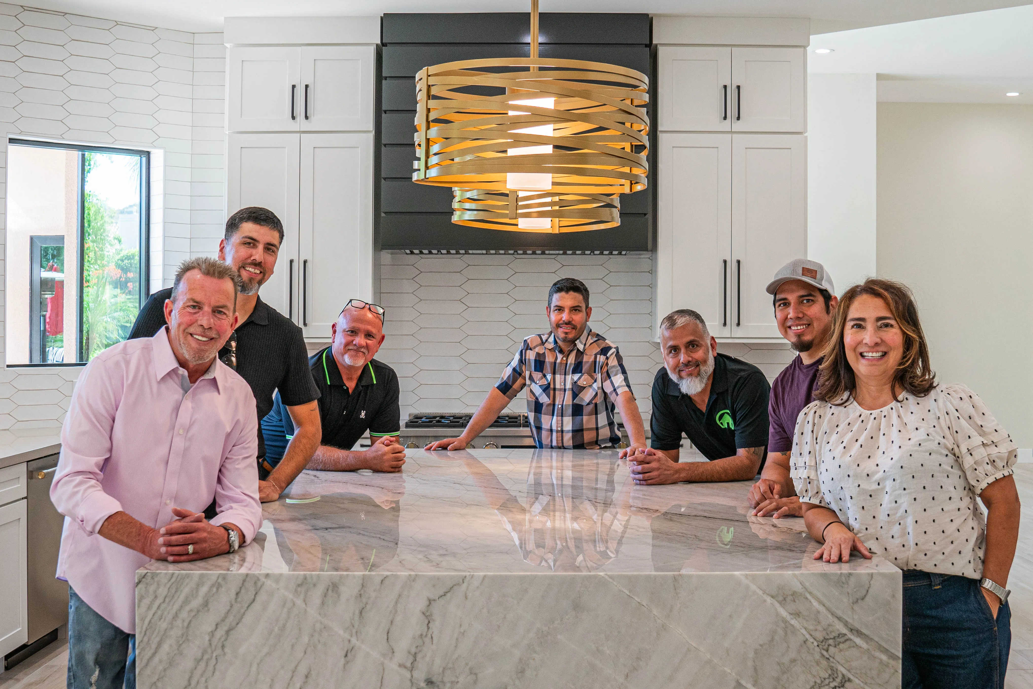 Picture of the entire team posing around a kitchen island.