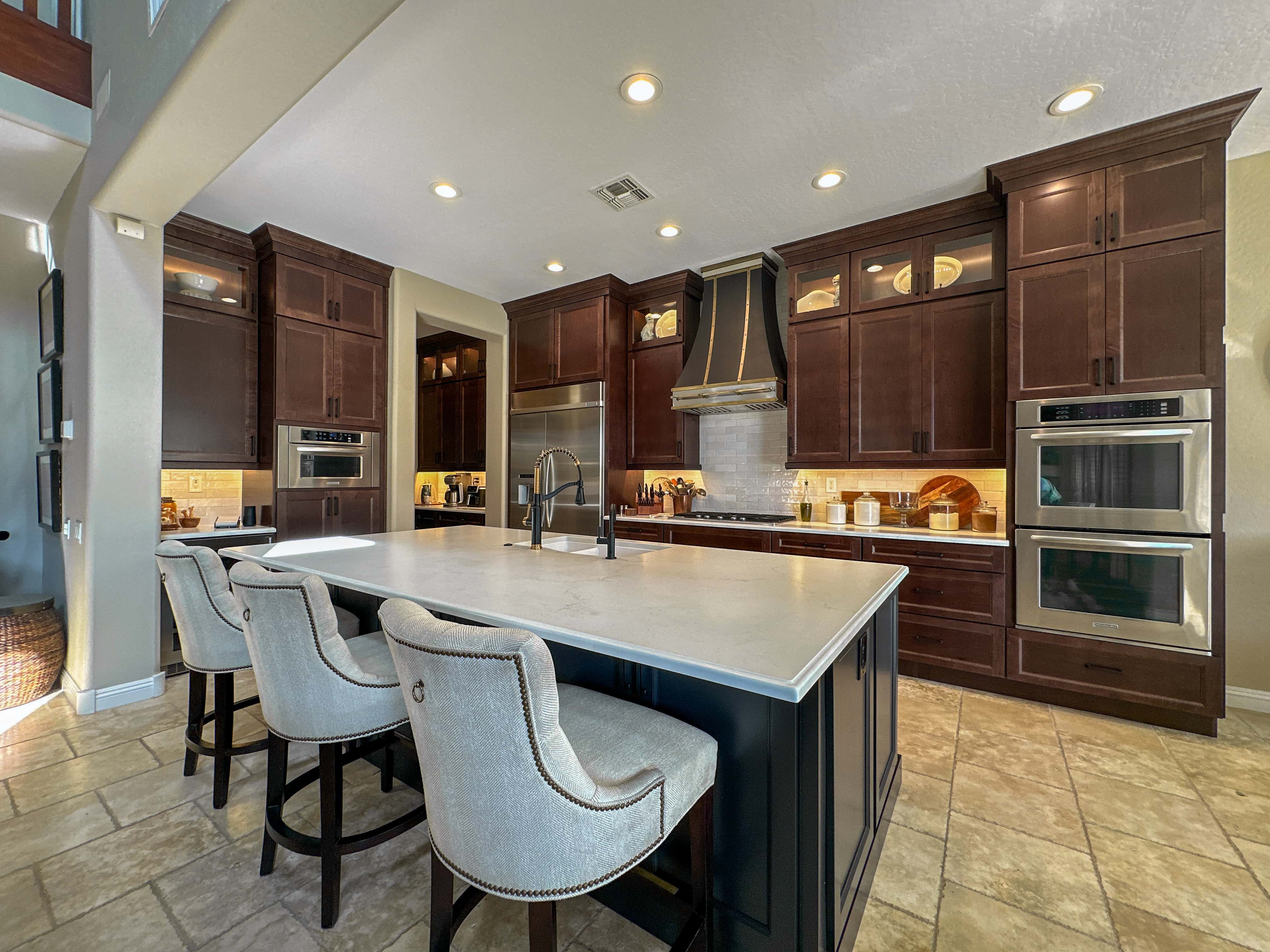 Picture of the Oppenheim kitchen remodel. Brown cabinetry with white countertops and a transitional vent hood. 
