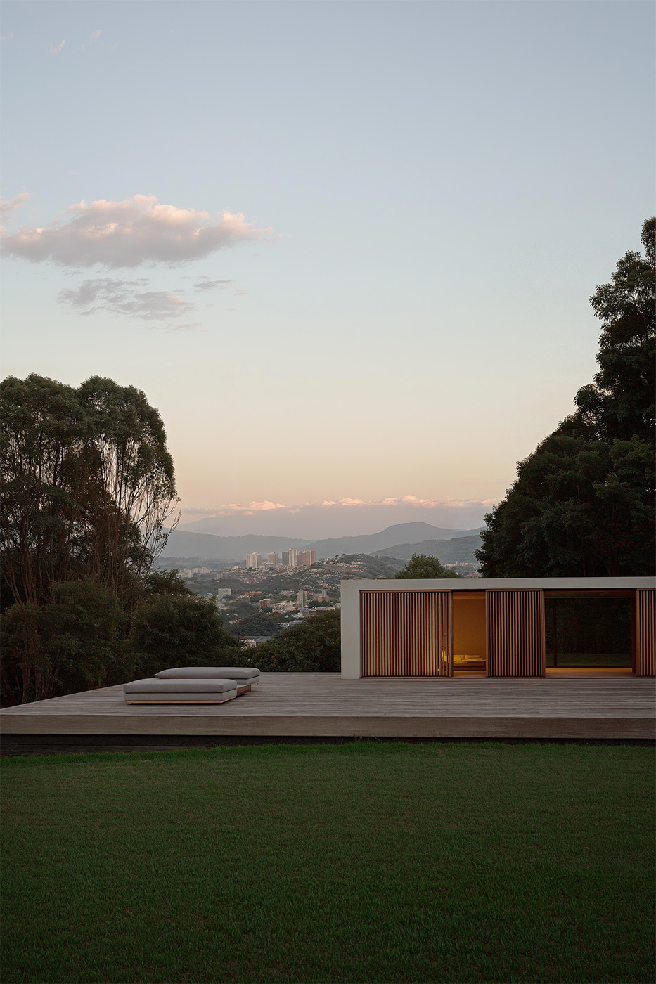 Minimalist modern house with wooden sliding panels and panoramic mountain view — architectural visualization of a luxury residence at sunset.