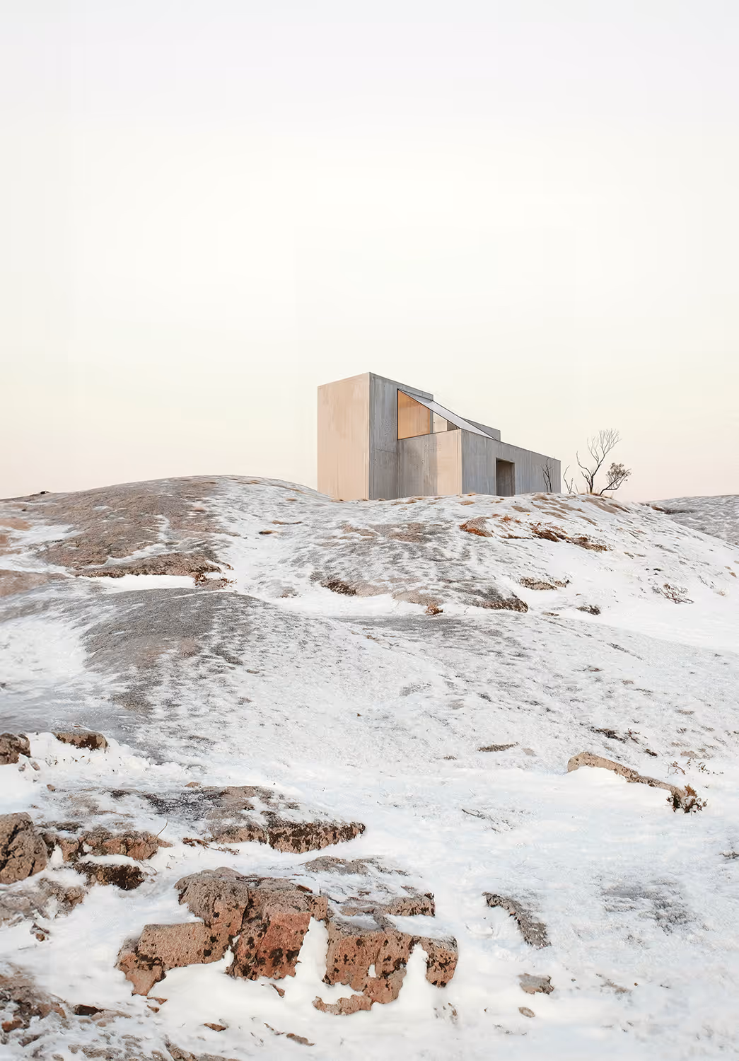 Brutalist concrete cabin in a snowy arctic landscape — minimalist winter architecture with geometric form integrated into frozen rocky terrain