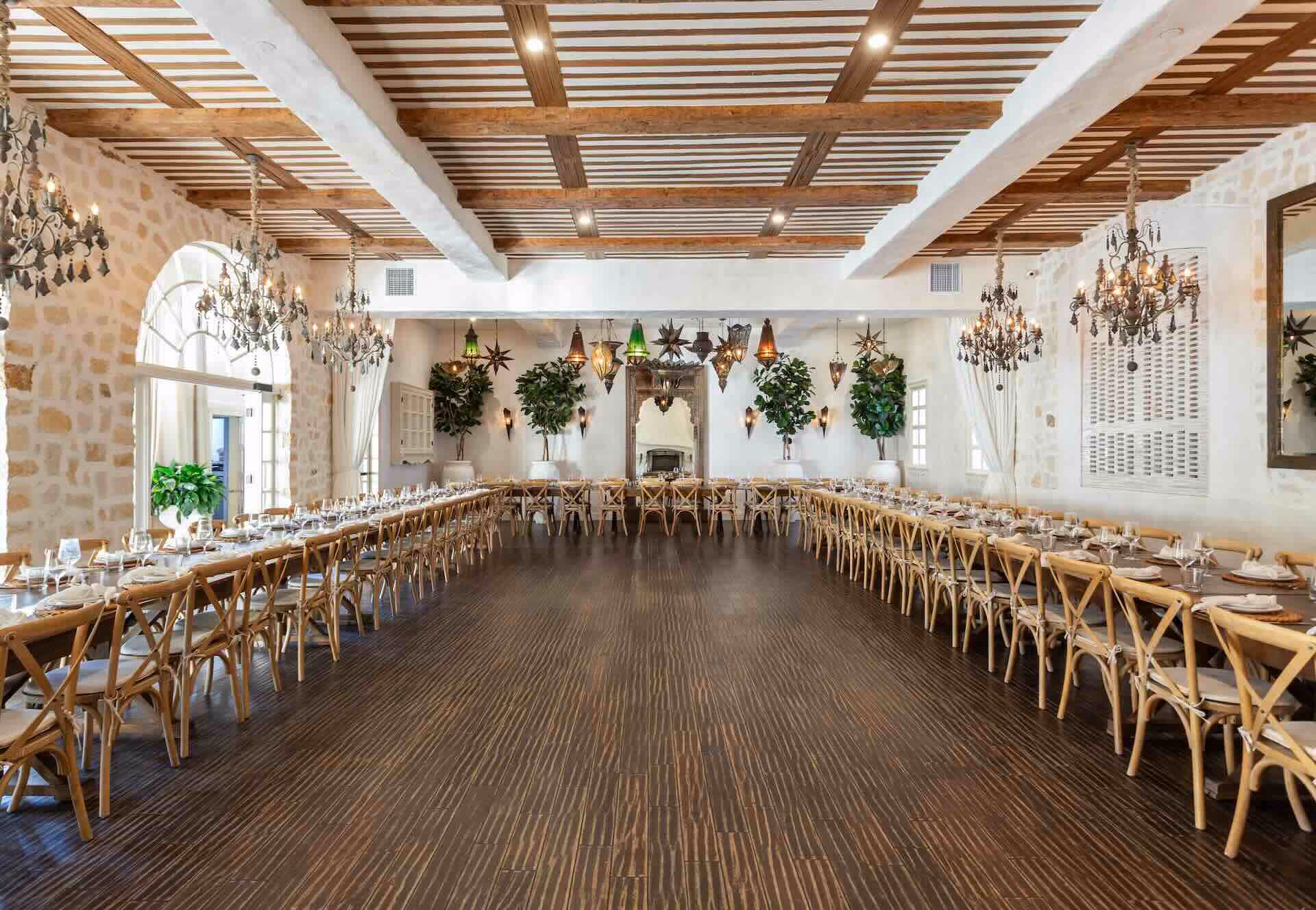 Spacious Main Room at Santuari LA with long banquet tables set for a private event under dramatic wooden beamed ceilings and chandeliers