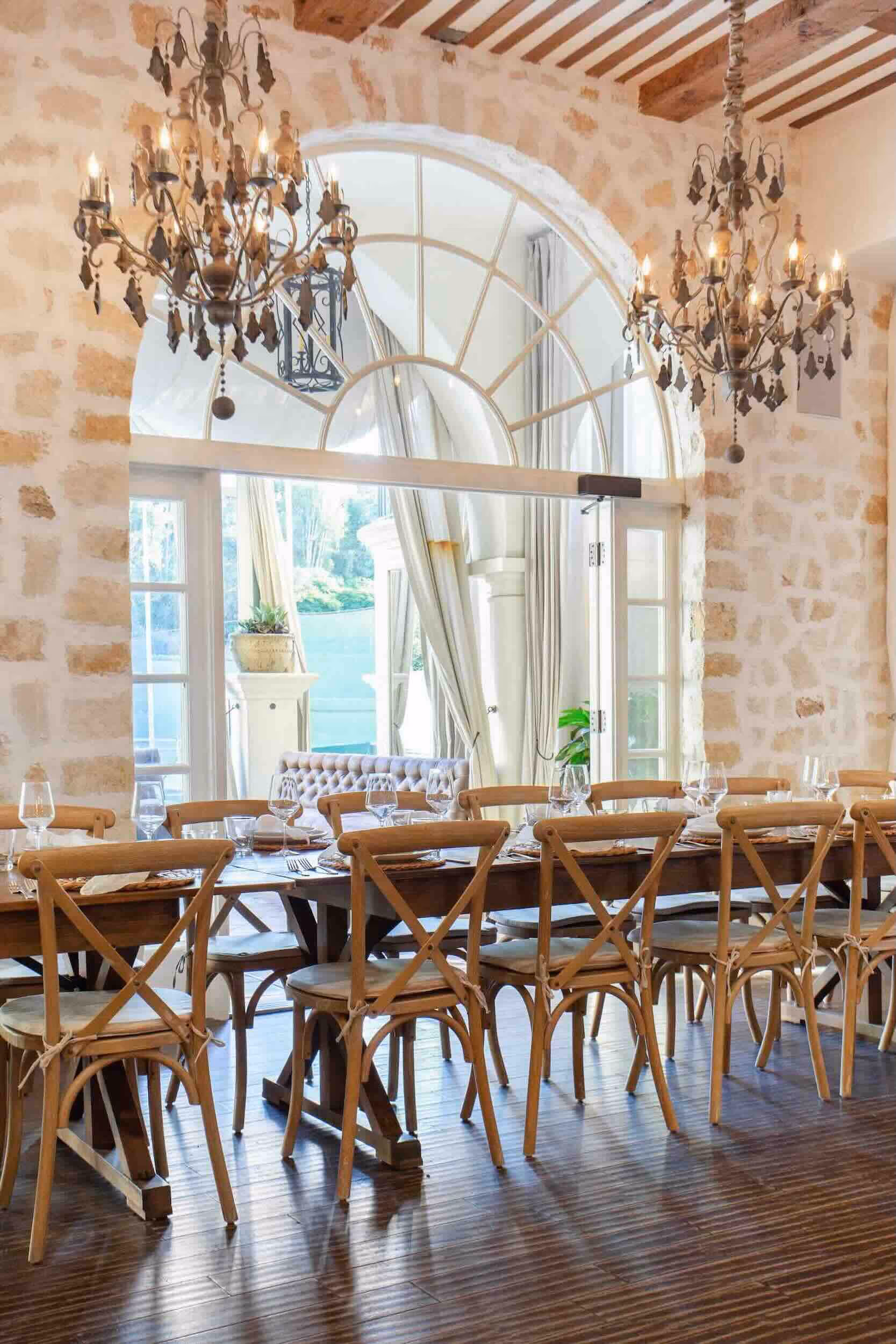 Main Room interior at Santuari LA looking out through large arched windows to the garden and Hollywood Hills, with beautifully set dining tables