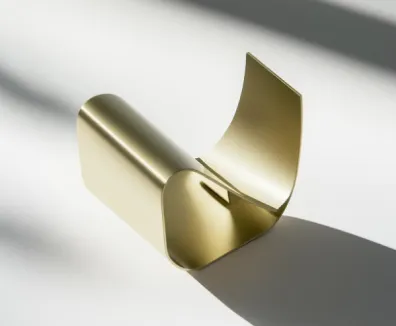 Minimalist gold metallic sculpture casting a shadow on a light surface.