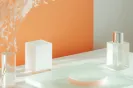 Minimalist skincare bottles and containers on a white surface with an orange background.