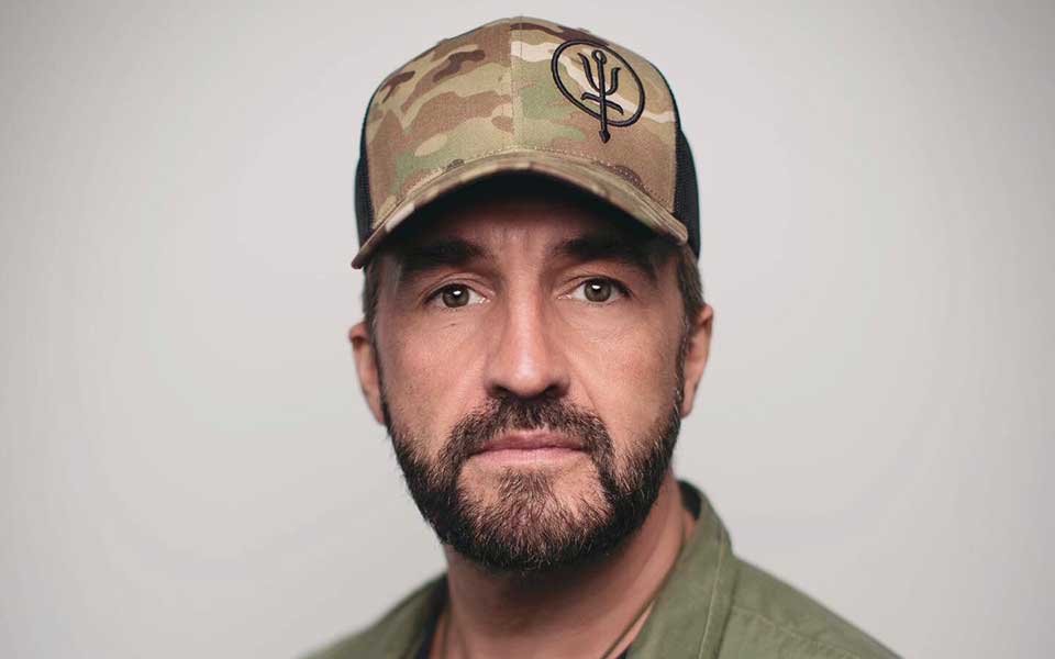a man with a beard wearing a camo hat