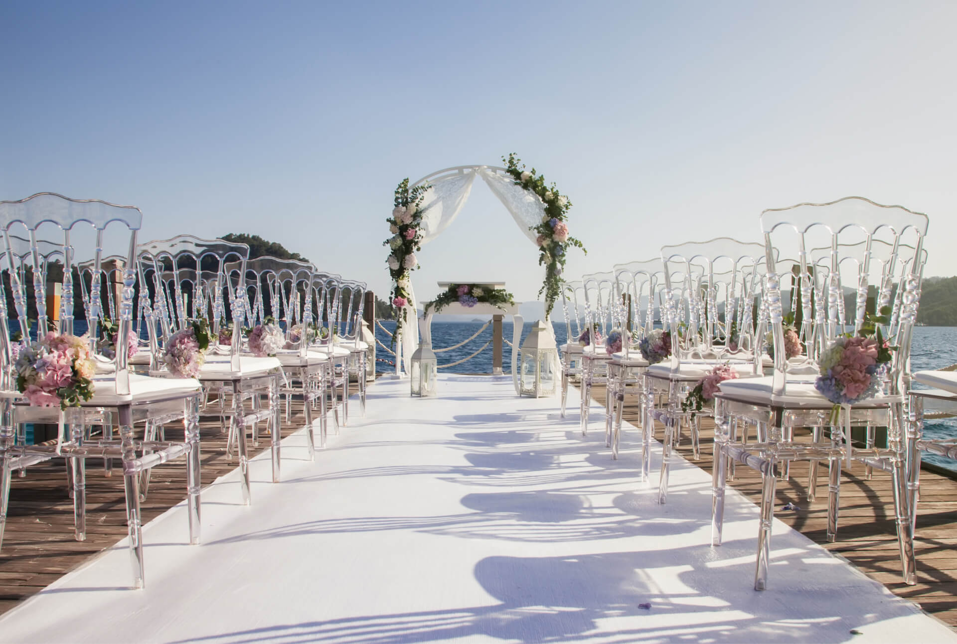 An outdoor wedding setup with white chairs and flowers.