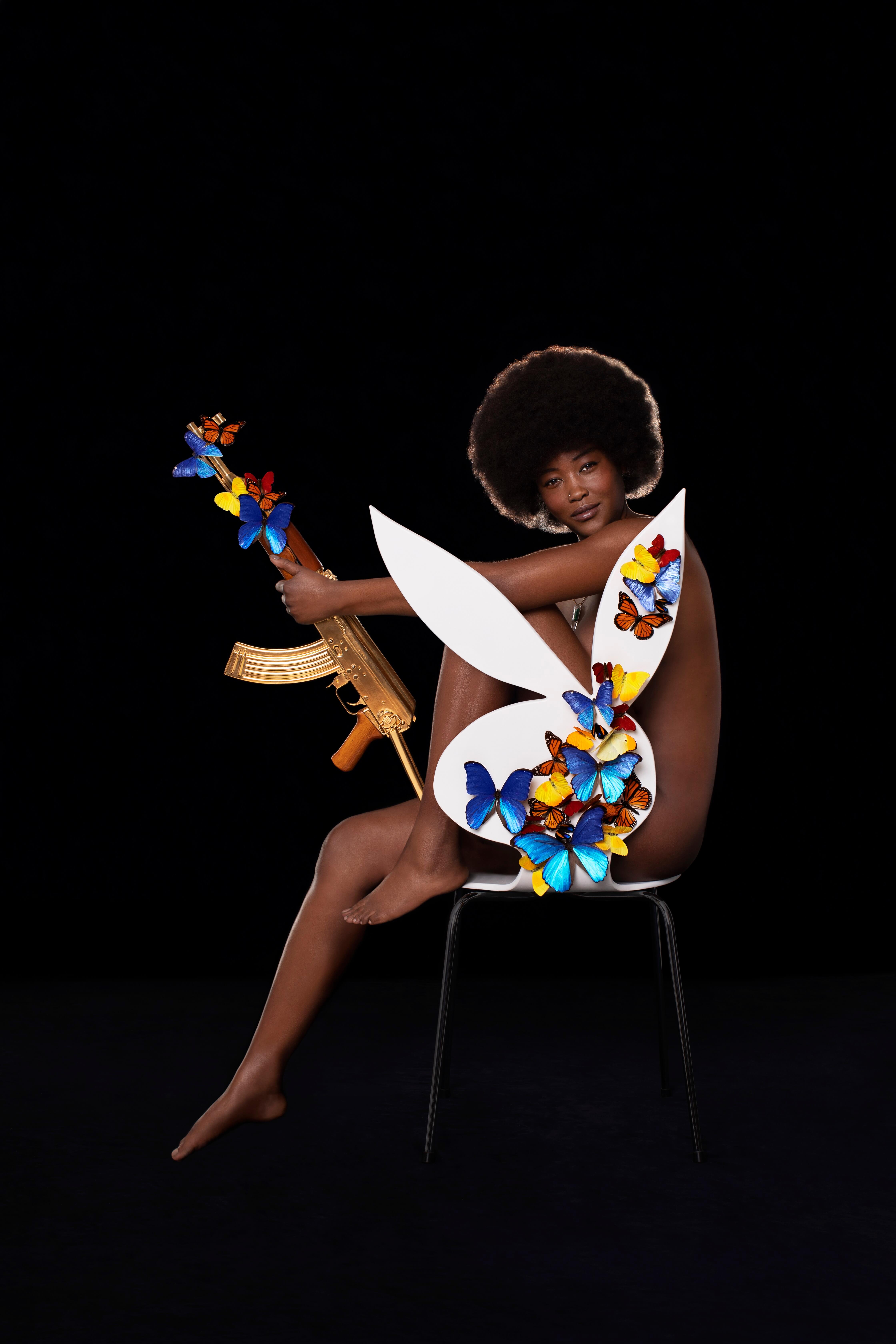 a woman sitting on a chair holding a gold-plated AK-47